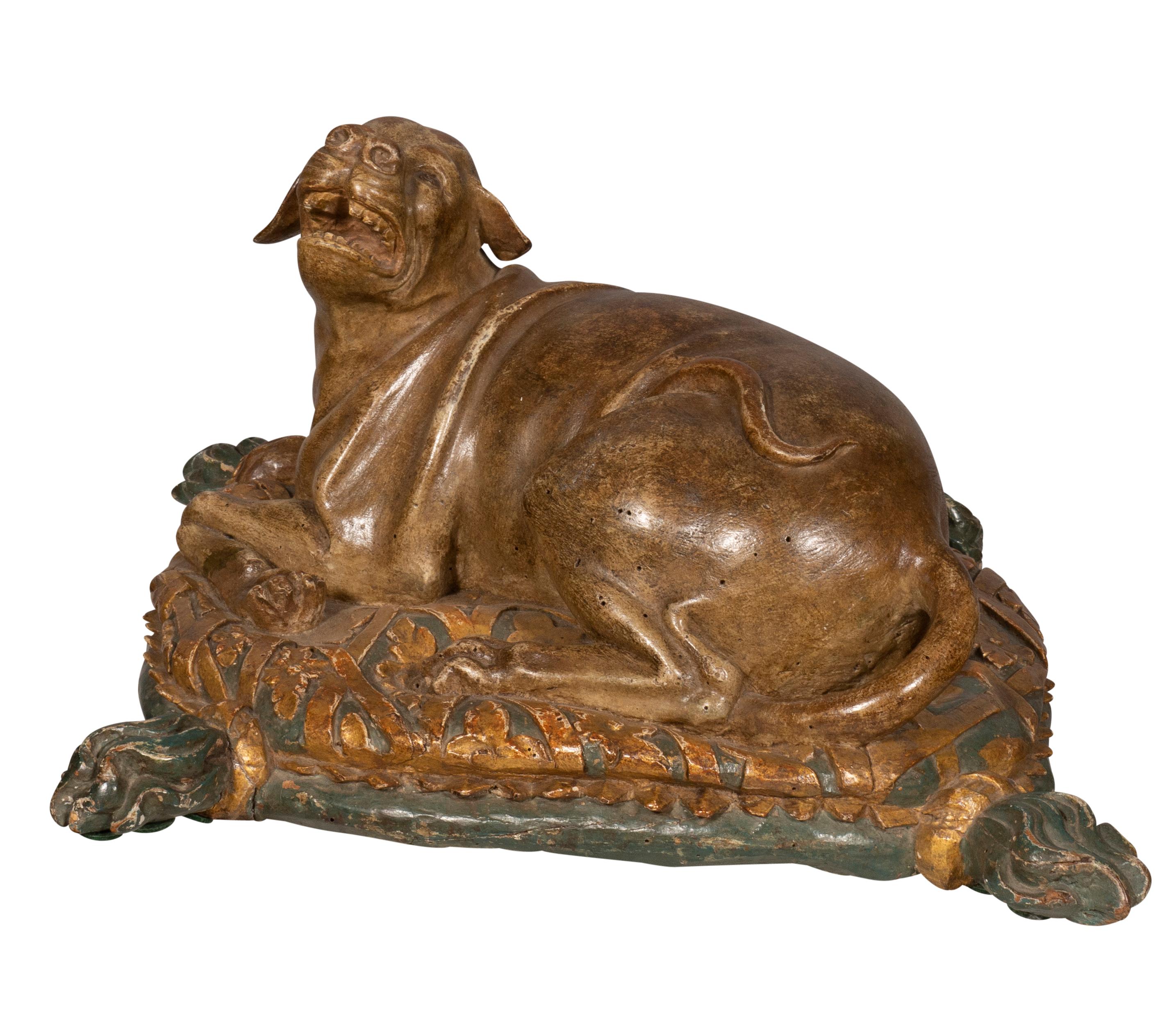 A well carved protective dog snarling on a gilded pillow with tassels.