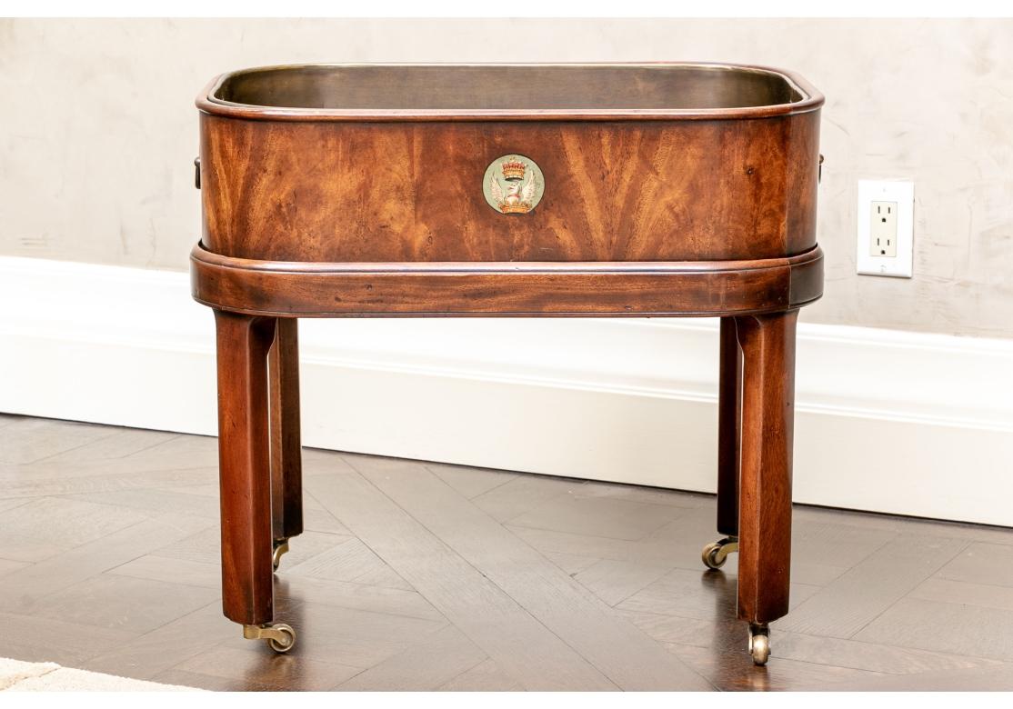 Originally purchased at Ann Morris Antiques, NYC. An oval bin form tray in figured wood with a painted crest with an eagle and crown on one side. Fitted inside with a metal removable bin with carry handles. The wood bin with brass side bale handles.