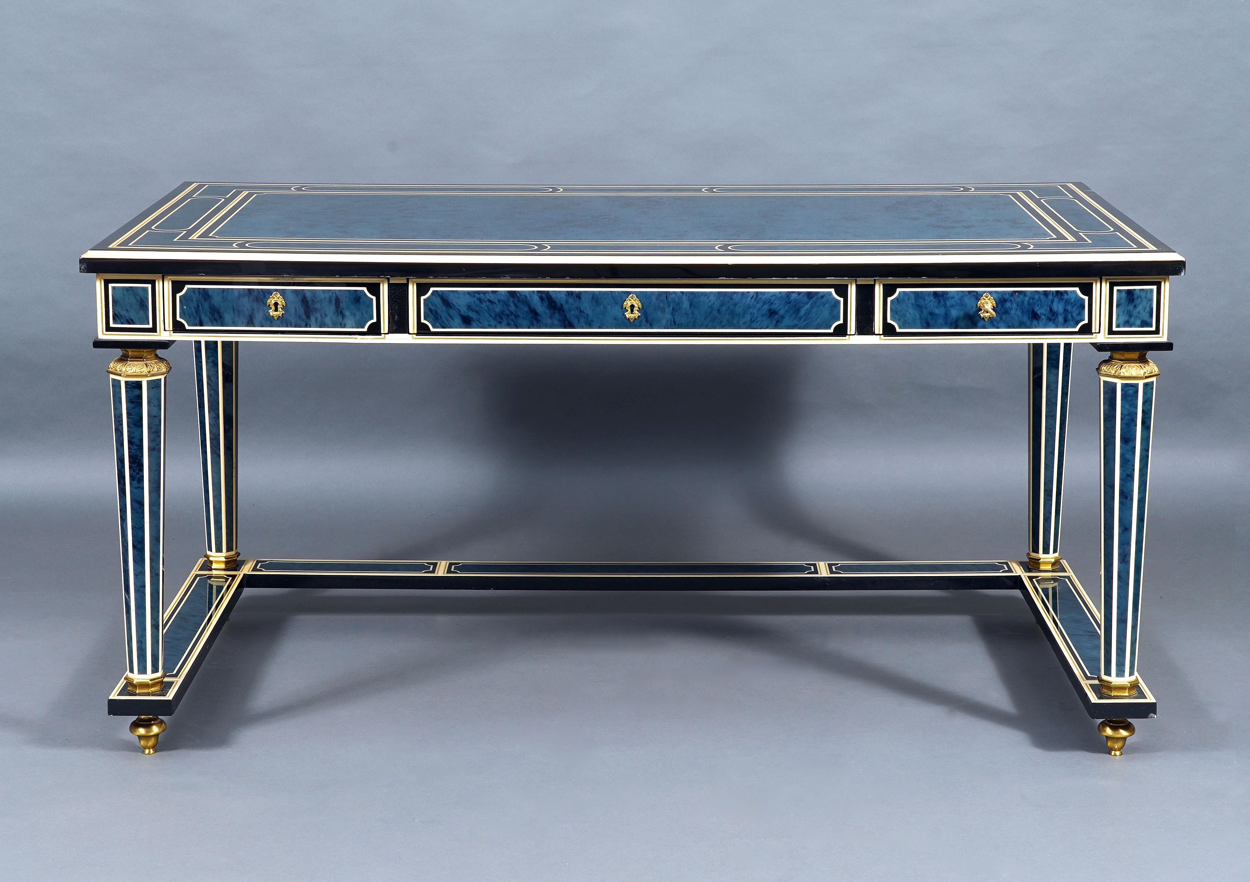 Fine flat desk decorated on all sides in lapis blue lacquered wood simulating tortoiseshell in geometric frames composed of a double net, one imitating ivory and the other brass, all on a black background. It opens on the belt with three drawers and