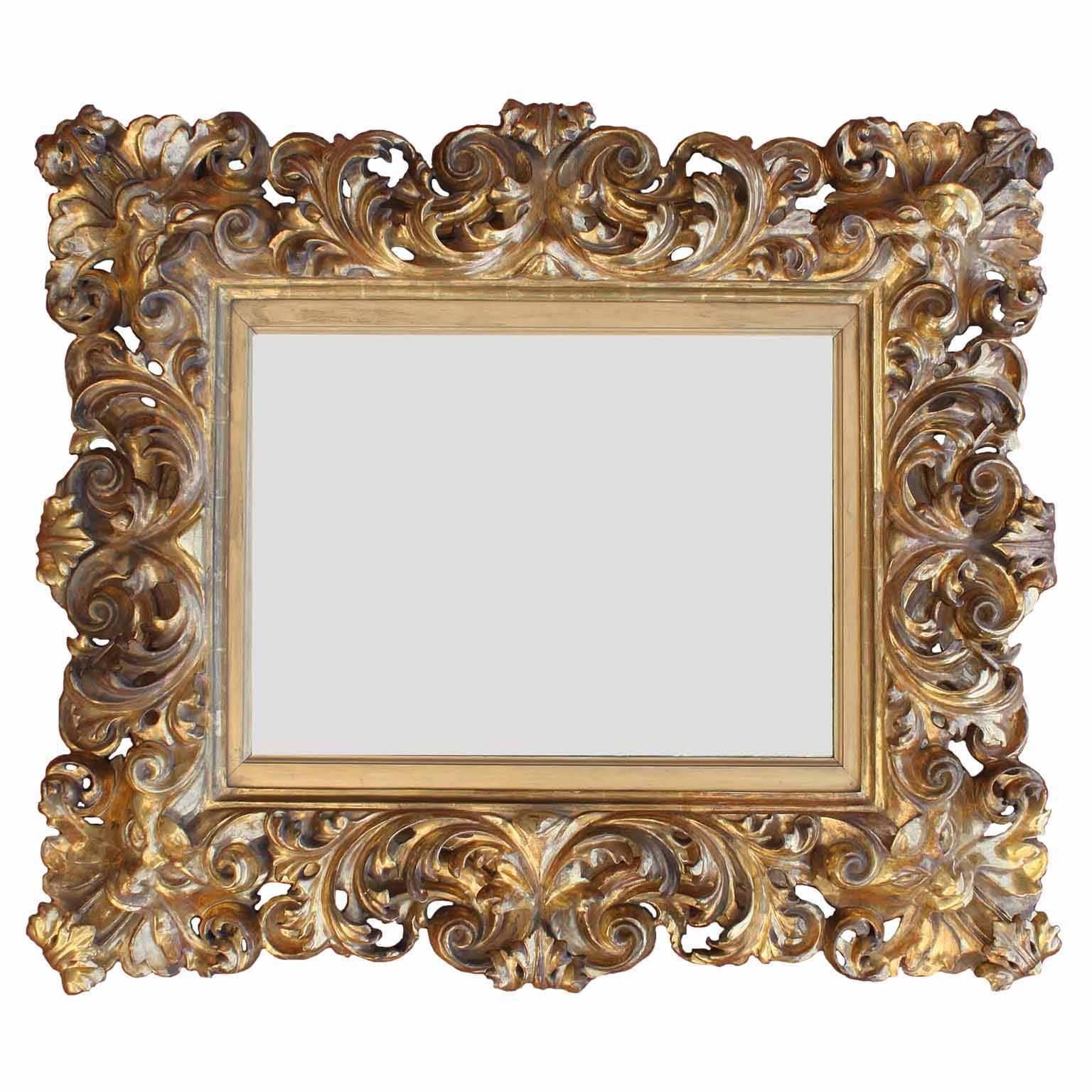 Cadre de miroir en bois doré sculpté de style baroque florentin du XIXe siècle, avec des masques allégoriques sculptés dans chaque coin, Florence, vers 1880.

 (Note : Ce cadre de miroir peut être accroché verticalement ou