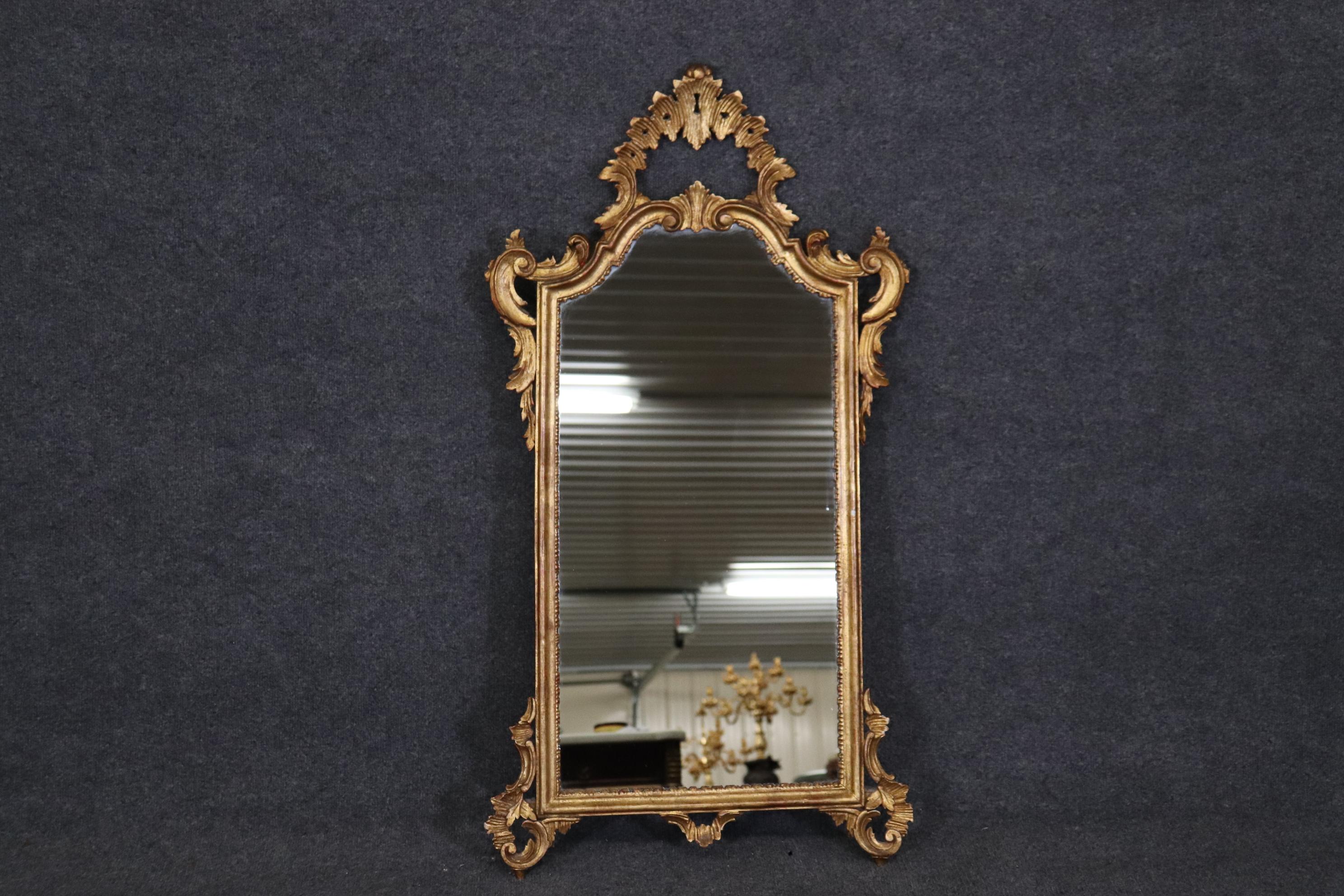 This is a gorgeous vintage 1960s era Italian made carved walnut mirror with genuine gold leaf and in good condition. The mirror measures 56.75 tall x 34.75 wide x 6 deep. 