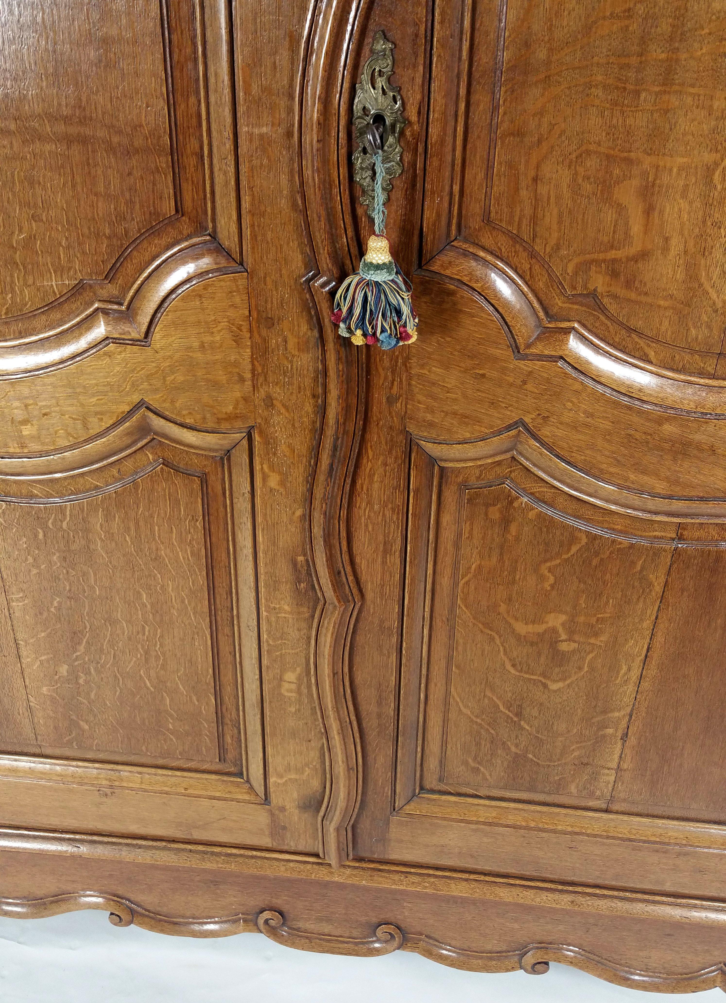 This outstanding and well-crafted French 18th century carved oak large armoire features shaped panelled doors with the original lock and key, as well as 2 removable shelves on the bottom. It is a ‘flat pack’ design, so it can easily be removed and