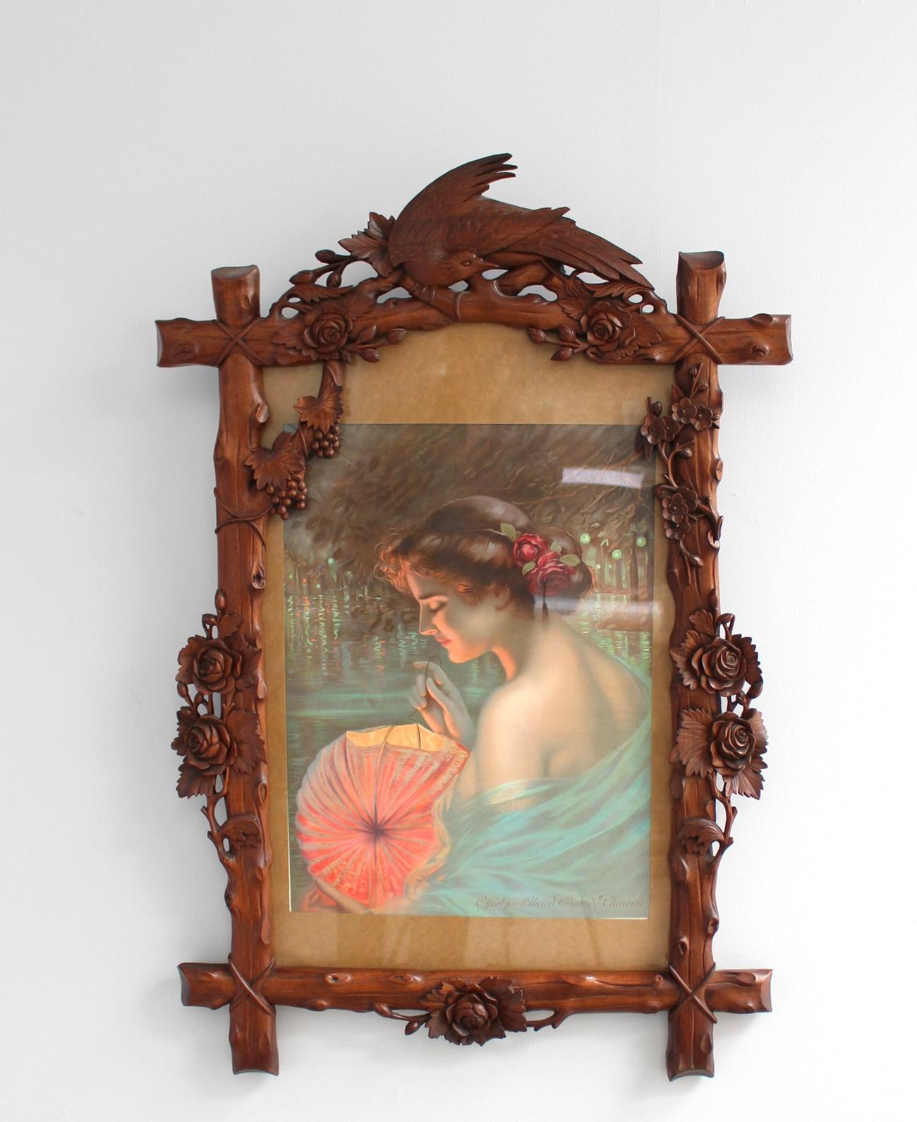 A fine French Art Nouveau hand carved and stained wood frame with flowers, grapes and bird, framing an original poster 