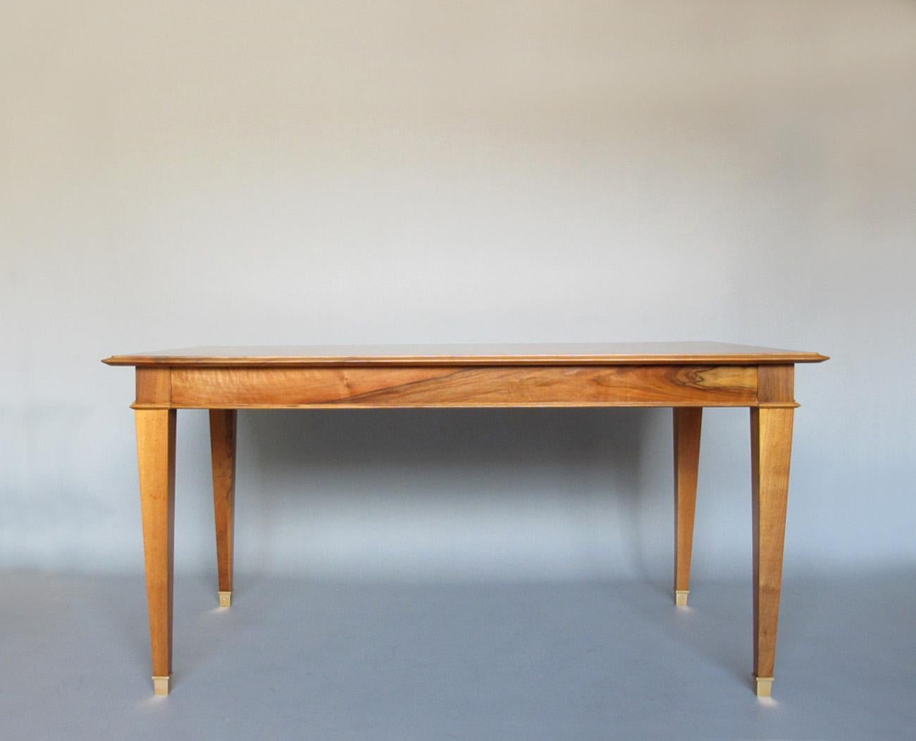 Fina mesa rectangular francesa de nogal de la década de 1940, con cuatro patas cónicas con sabots latonados, y dos cajones en los extremos que sostienen las hojas de los extremos.
           