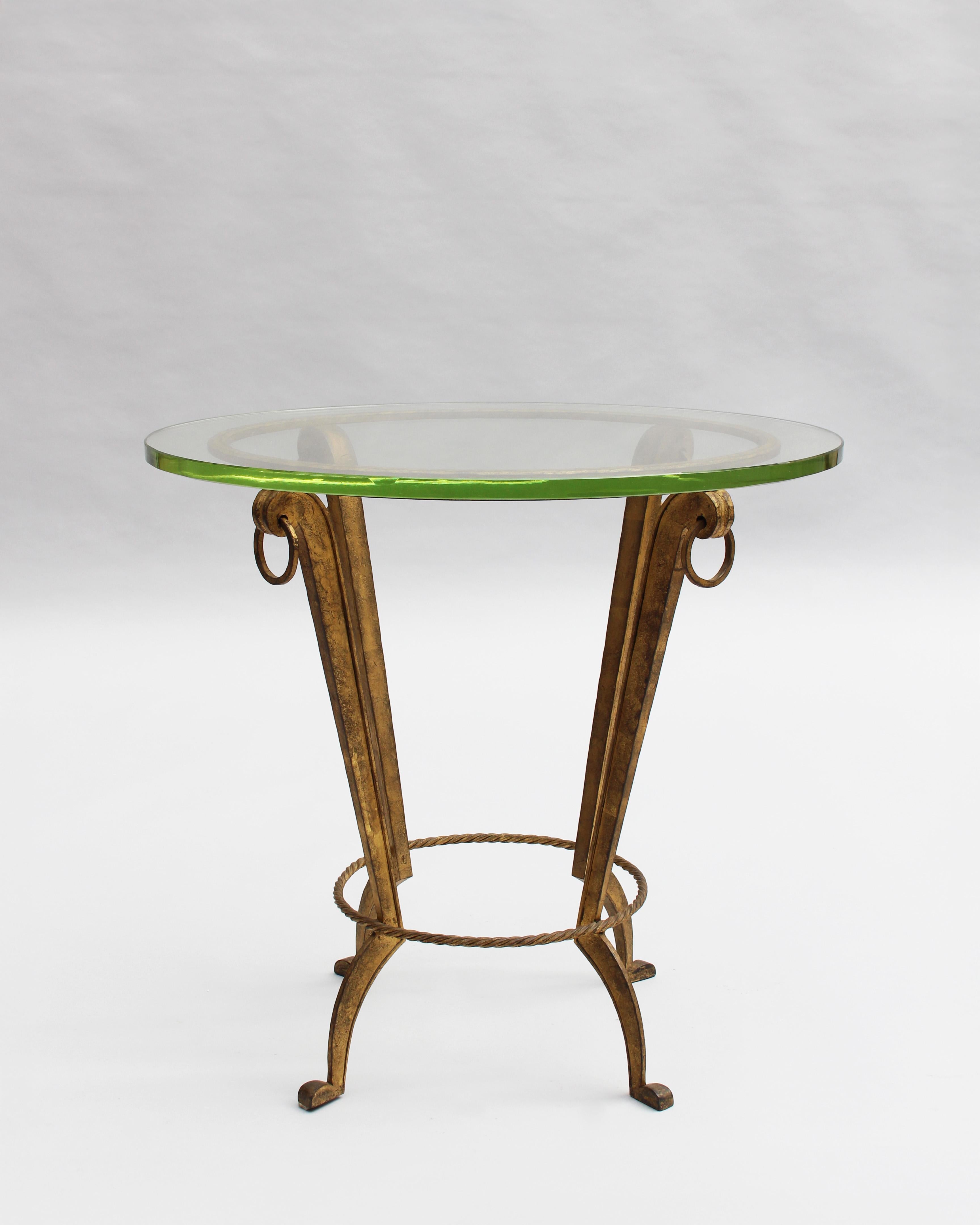 Maison Ramsay - A fine French 1940s gueridon / side table with a gilded patinated wrought iron base that supports a round glass slab top. 