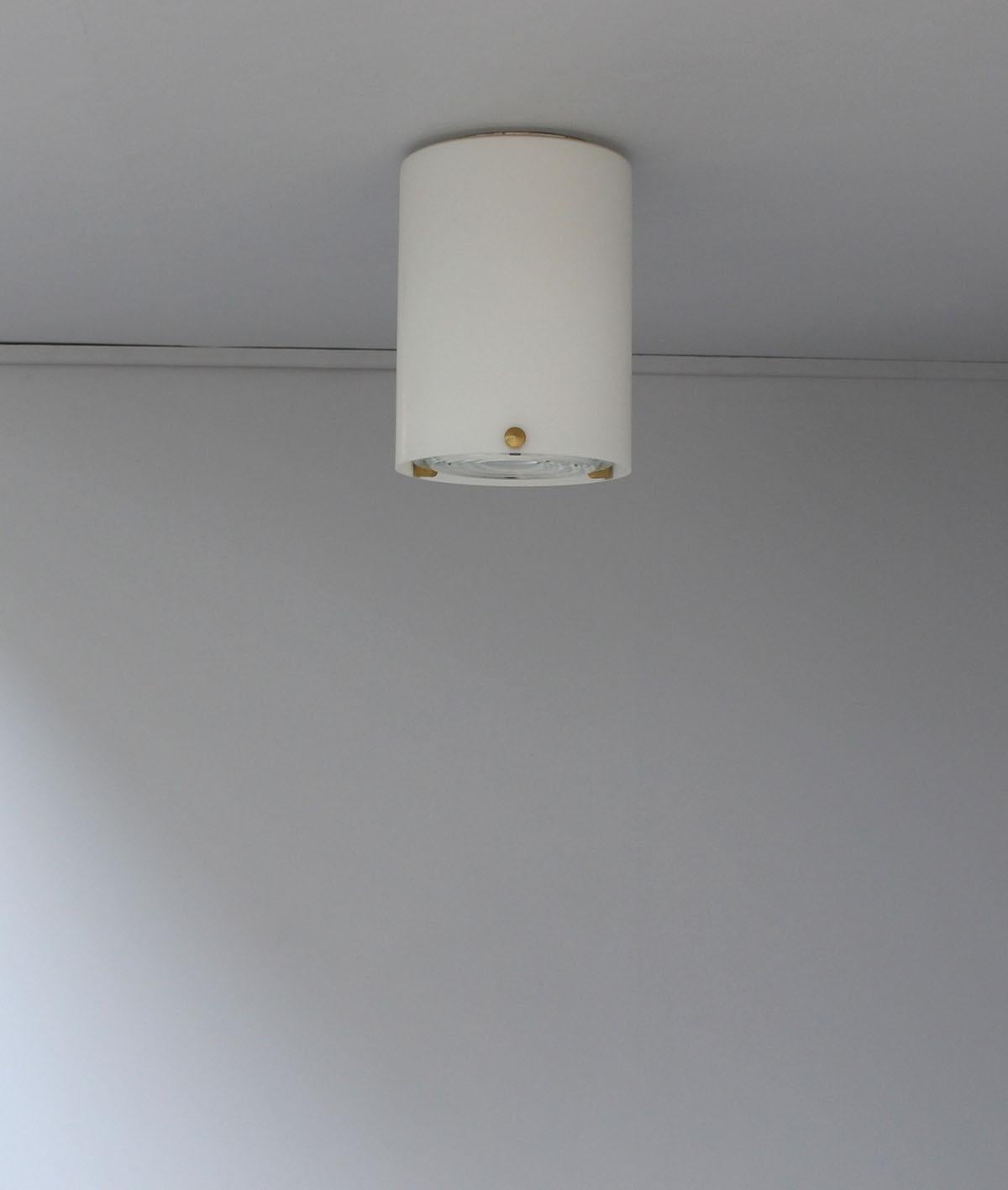 Jean Perzel - A fine French mid-century cylinder-shaped flush mounts / ceiling lights in satin enameled glass with three brass studs that support a prismatic glass lens.
   