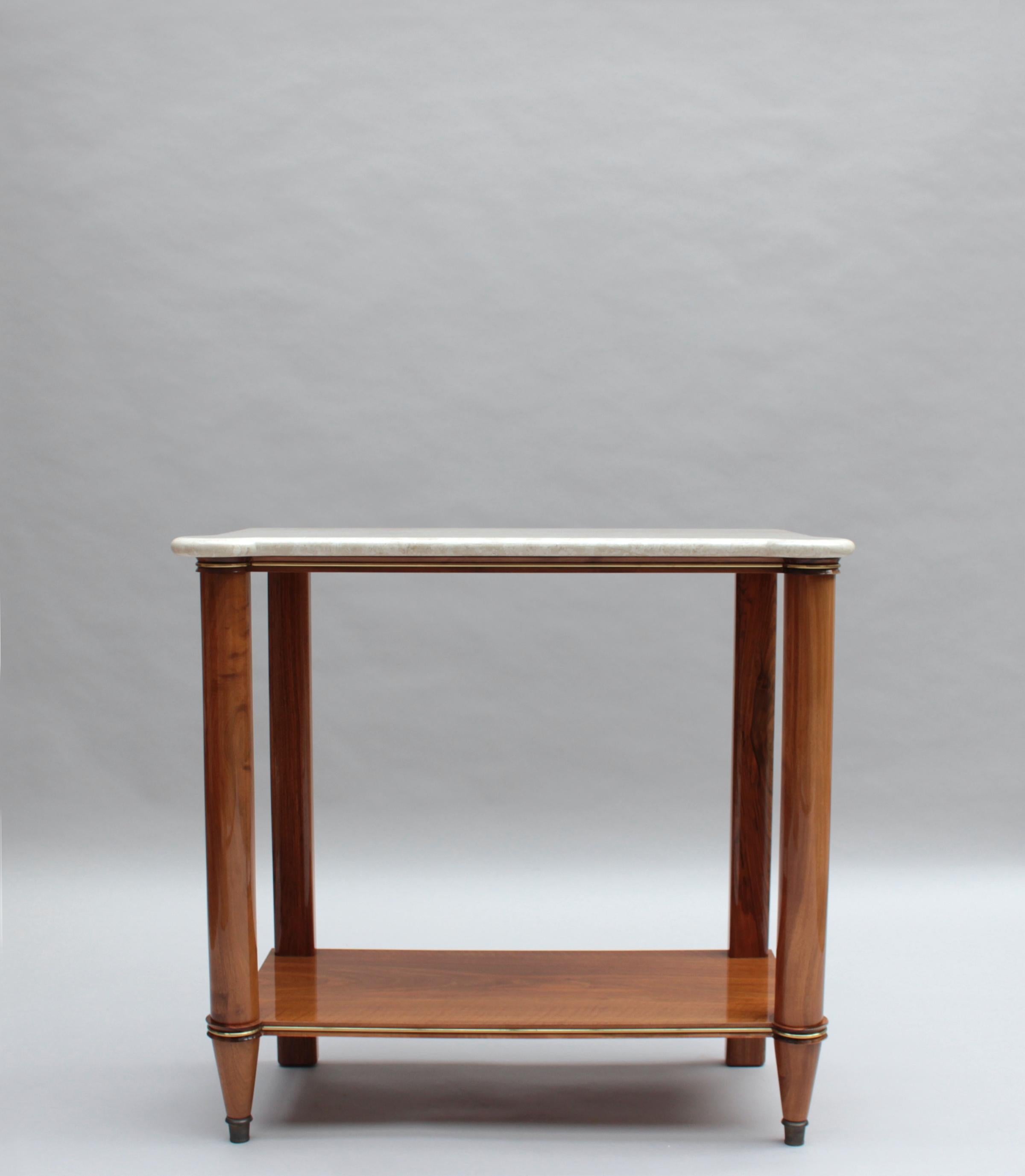 A fine French Mid-Century two-tiered walnut console with a marble top and brass details.
Given the wood underneath the marble is finished and shows some visible cut dowels suggests that the console might have been a three-tiered shelving unit