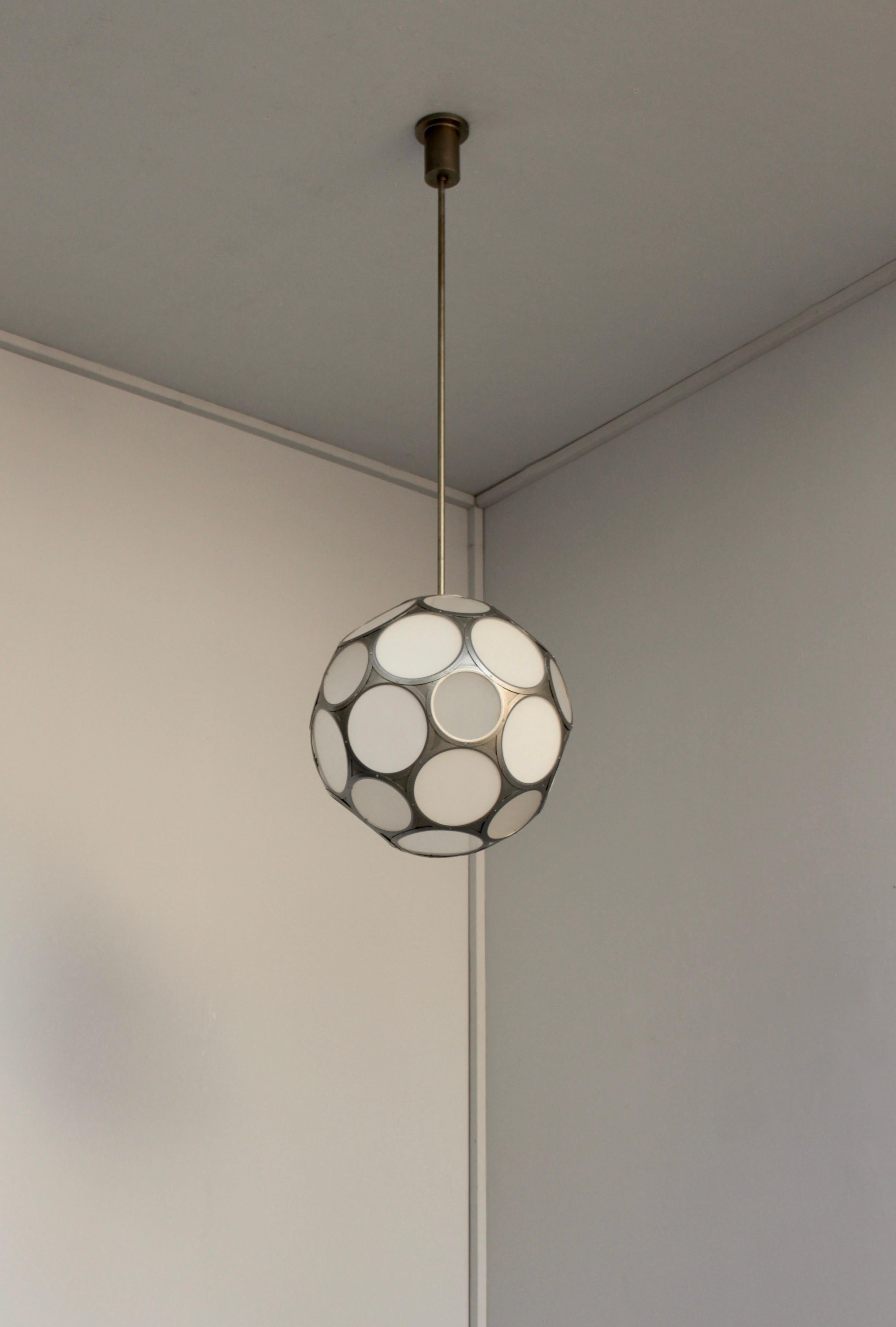 Atelier Jean Perzel - Un raffinato pendente francese di metà secolo con inserti in vetro bianco smaltato e smerigliato che formano una sfera sfaccettata sospesa da una struttura in metallo patinato, asta e baldacchino.

  