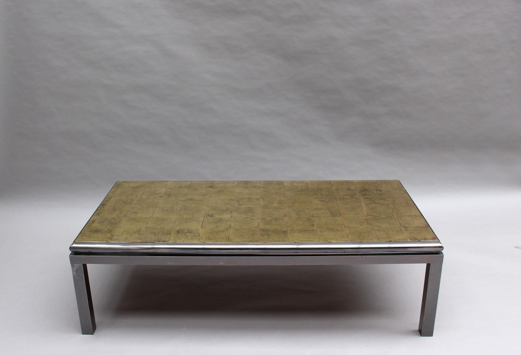 A fine French mid-century coffee table with a blackened patinated chrome metal frame and an églomisé glass top.
Commonly attributed to Guy Lefevre for Maison Jansen.