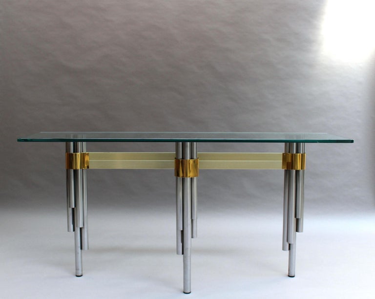 Philippe Jean - A fine French Mid-Century sofa table with a sculptural tripod base formed of bundles of tubular stainless steel rods that support a glass top. 
Signed.
