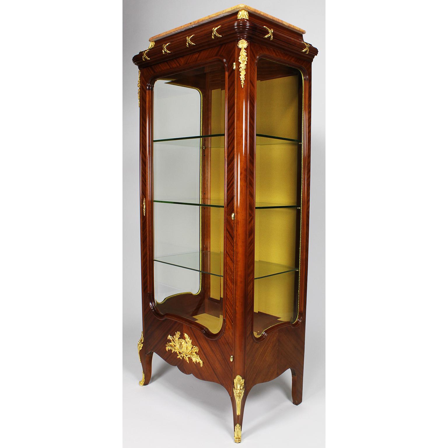 A Fine French 19th-20th century Louis XV style ormolu-mounted tulipwood vitrine with marble top, in the manner of François Linke (1855-1946). The slender single door cabinet fitted with a veined peach-color marble top, three interior glass shelves