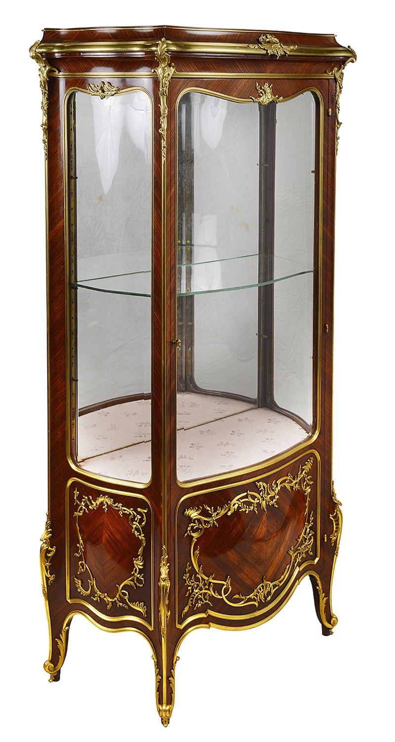 A fine quality French 19th Century Louis XVI style bombe fronted vitrine / display cabinet. Having wonderful scrolling foliate gilded ormolu mounts, bombe shaped glass to the front and sides. Glass adjustable shelves within, a single door to the