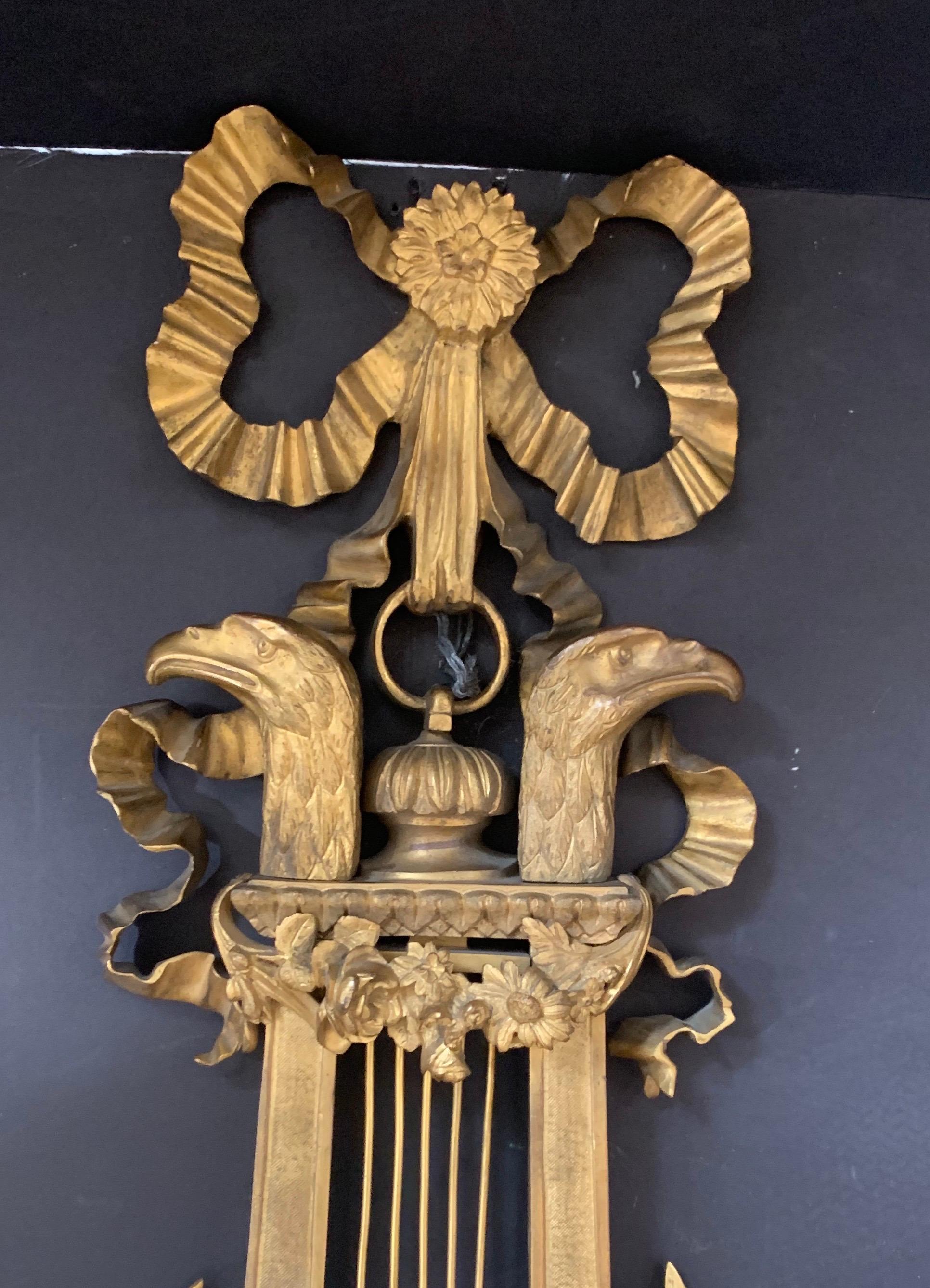 A wonderful, finely chased in gilt bronze Cartel wall clock, made in France at the end of the 19th century.
This Louis XVI clock presents a refined bronze chisel. In the shape of a zither, it is adorned with heads of birds of prey, splendid roses,