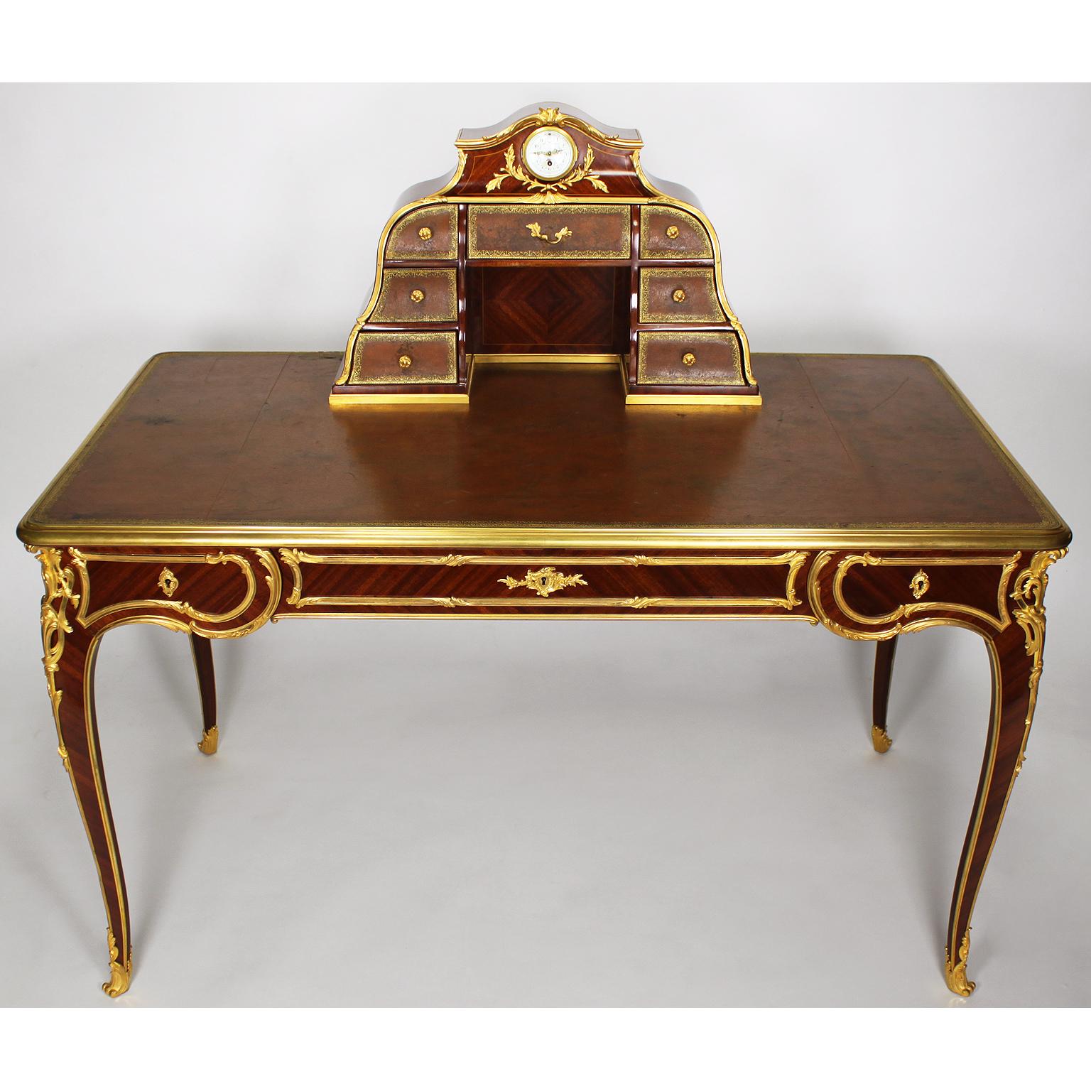 A very fine French 19th century Louis XV style bureau plat (Desk - Writing Table - Ladies Desk) Cartonnier by Antoine Krieger, the quarter-veneer satiné with fruitwood stringing, the cartonnier set with a circular timepiece above seven gilt-tooled