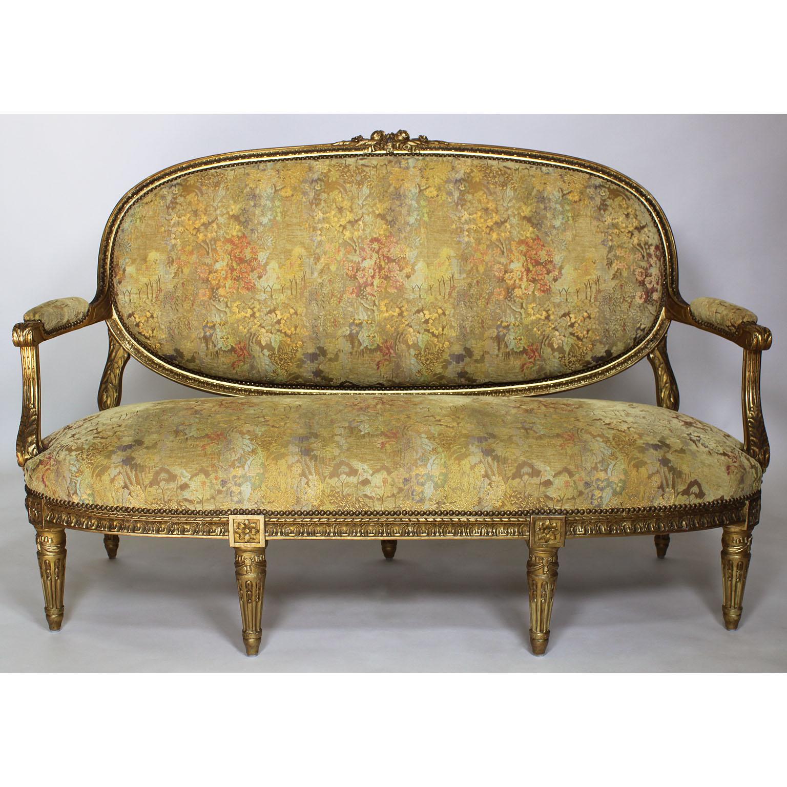 A very fine French 19th century Louis XVI style giltwood carved five-piece salon suite, comprising of a canapé and four fauteuils, all with recent upholstery. The finely carved frames with paneled back, padded arm supports and seats, with ribbon