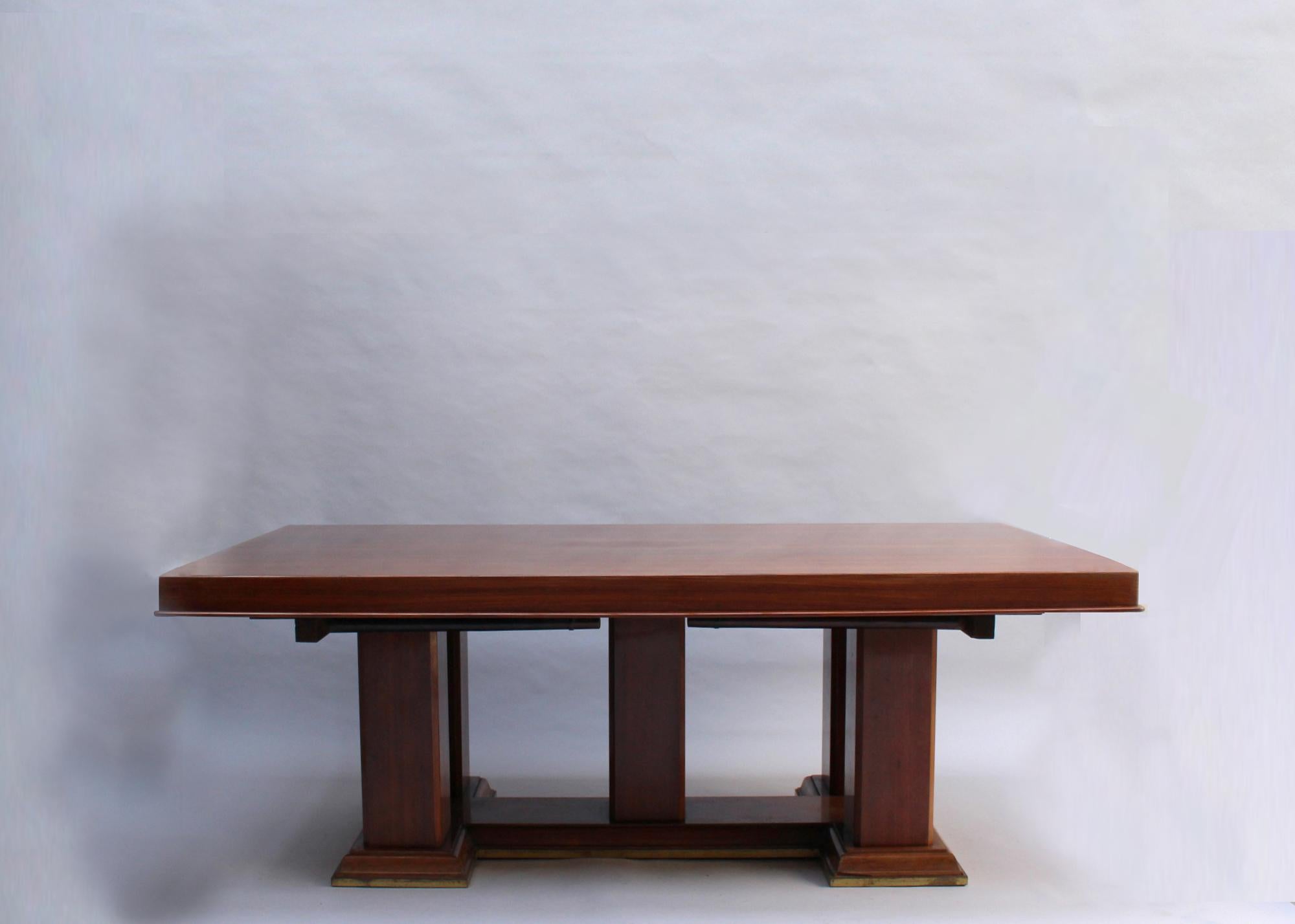 Mounted on a five-pedestal mahogany base with bronze details, the table can receive four end leaves for a total length of 13'2