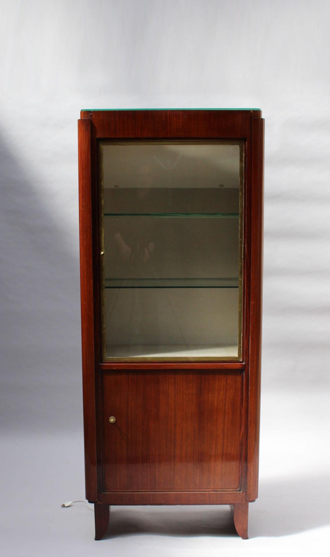 A fine French 1030s rosewood vitrine by Maxime Old with a plain lower door and a bronze framed upper glass door opening on an upholstered interior with glass shelves. Inside lighting for the shelves plus another lighting coming from inside the glass