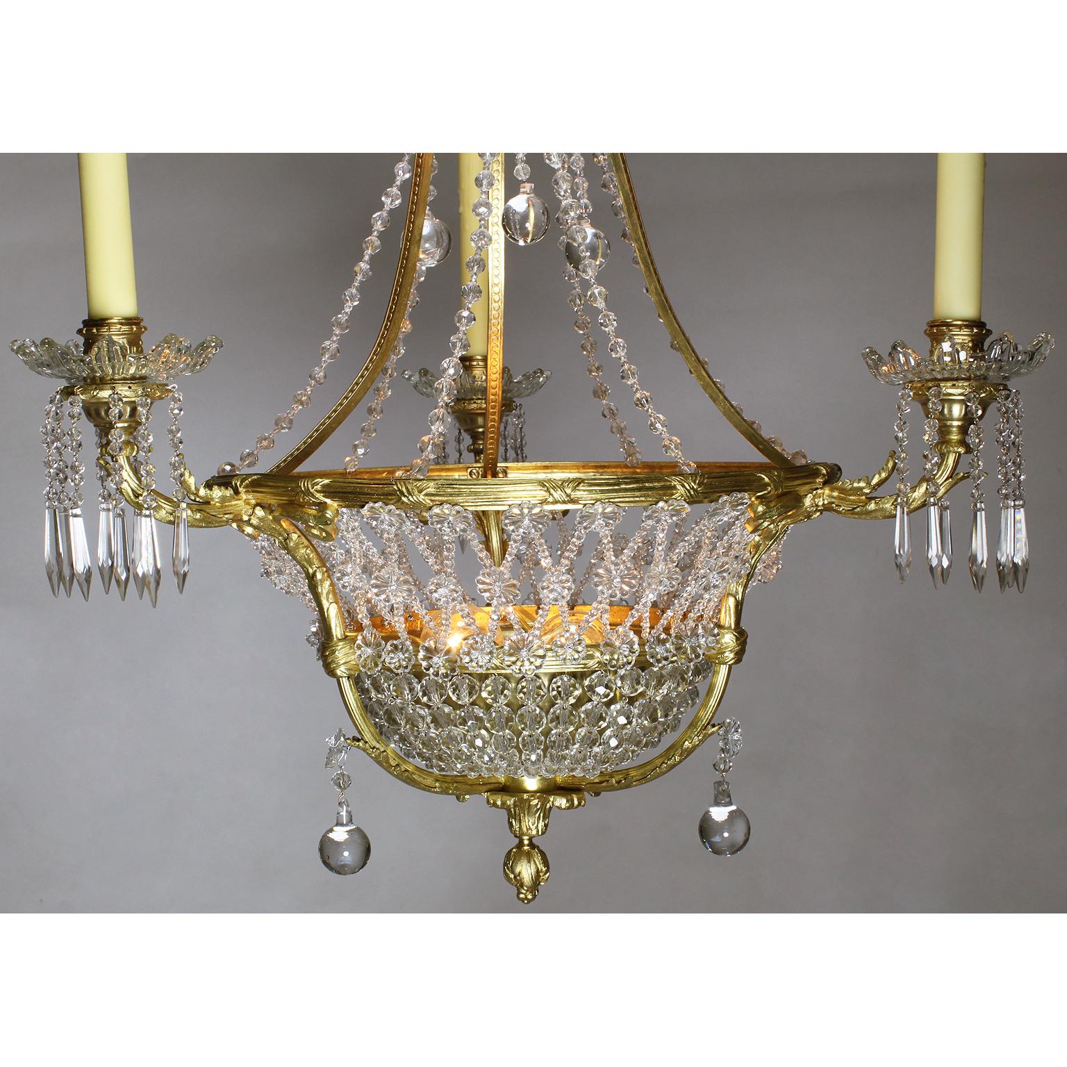 A fine French Belle Époque 19th-20th century three-light gilt-bronze and cut-glass basket chandelier. The circular basket shaped banded gilt-bronze frame surmounted with three scrolled candle-arms and two interior lights, all decorated with weaved