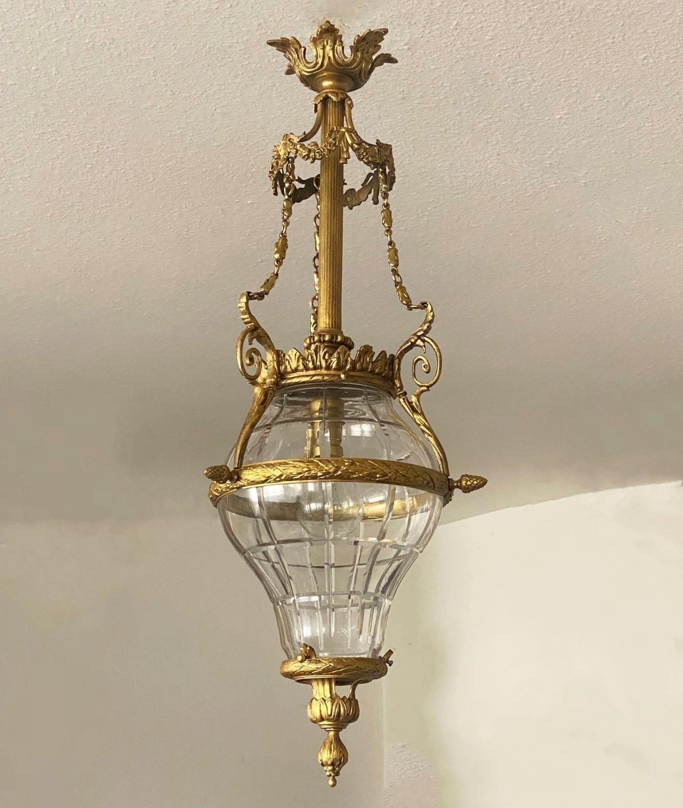 A fine gilt bronze and molded cut-glass lantern in Belle Époque style, France 1900-1910.  The molded and cut-glass body surrounded by finely elaborate bronze detailling with a crown conneting the top by three beautiful chains to a second floral