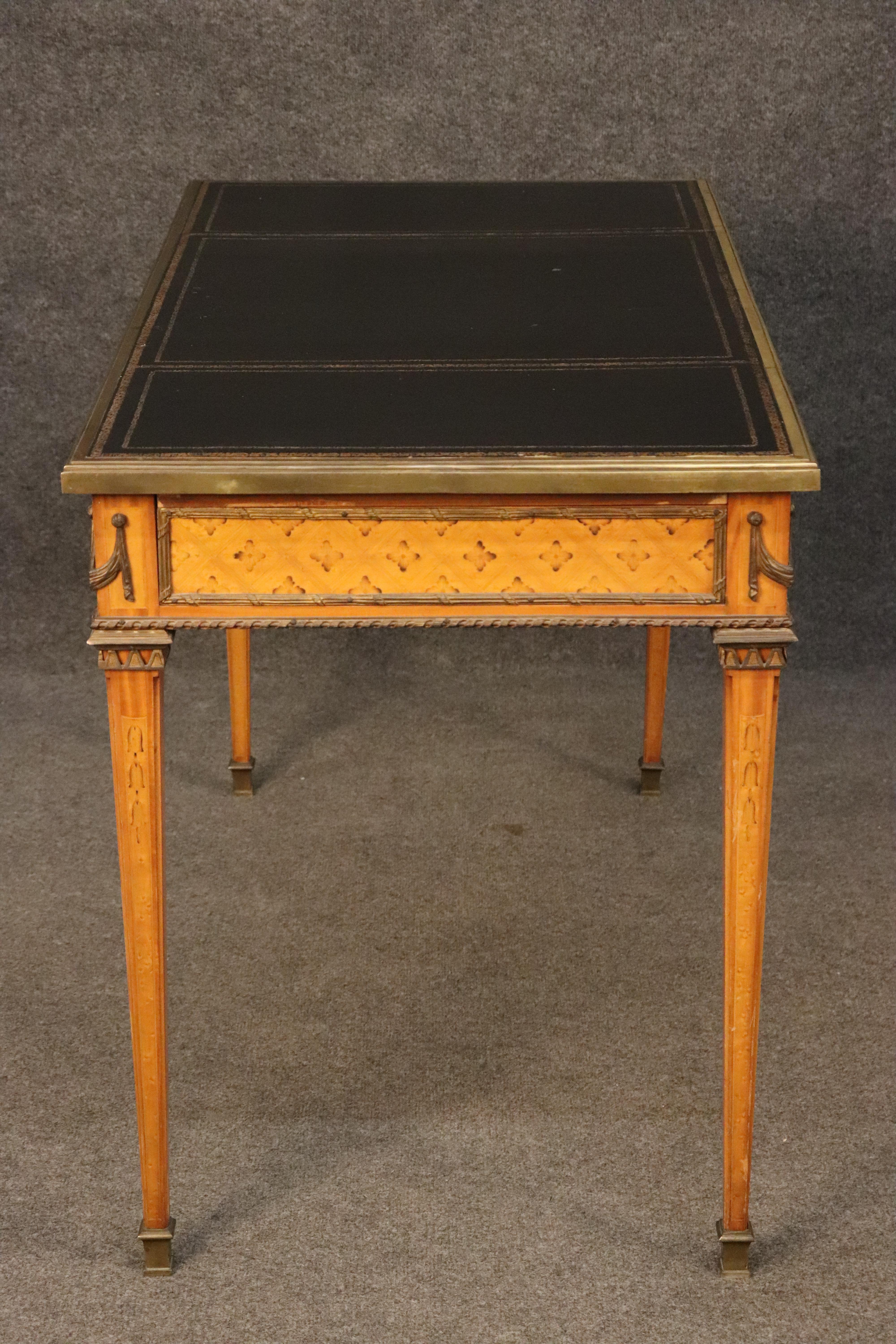 This is a superb, French Directoire style desk. The desk is adorned with bronze and brass ormolu and a gorgeous gold tooled leather embossed top. The desk features inlaid burnished tulipwood flowers and a fantastic walnut case. The desk is in