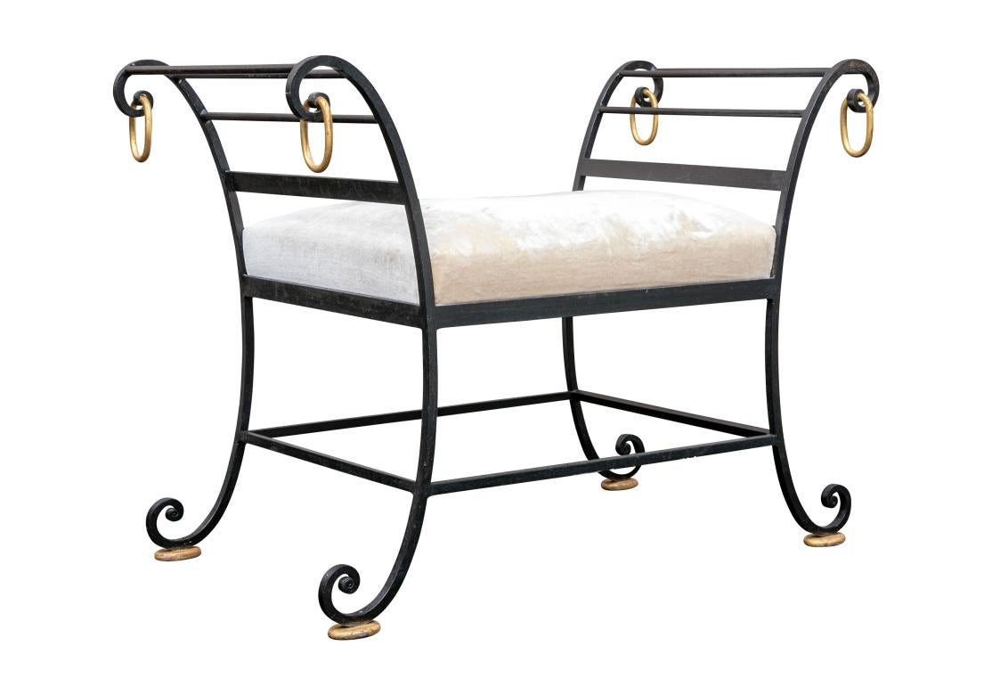 A particularly fine French Hollywood Regency Era Scrolled Iron Bench with Gilt Accents dating to the 1930’s. The Bench features a fine Classical form, good weight and surprising comfort. Four dangling Oval Rings hang from the scrolled arms and the