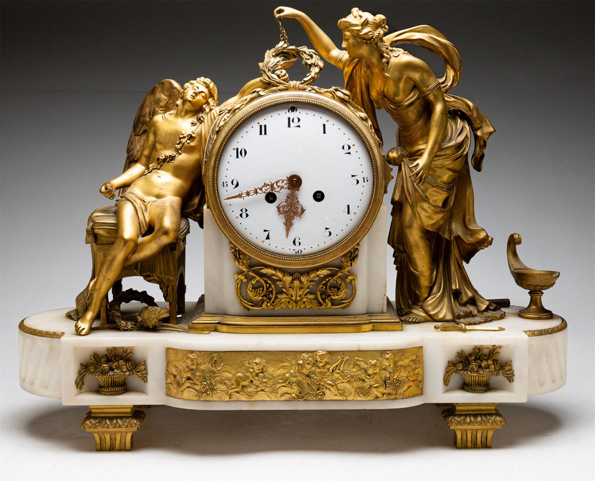 A Fine French gilt bronze and marble clock from the second-half of the 19th Century. A central round enameled clock face with Arabic numerals is flanked by a seated Eros and standing Psyche, moments before she lights the oil lamp so she may see