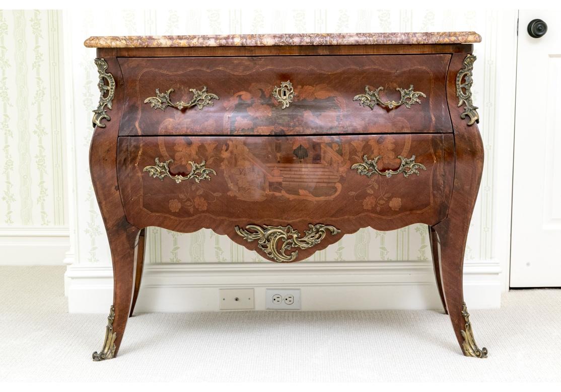 Una cassettiera classica francese Bombé a due cassetti dalla forma tradizionale, con elaborate montature e rosette in bronzo e piano in marmo sagomato di colore viola. L'immagine frontale raffigura una coppia che si tiene per mano su una scala