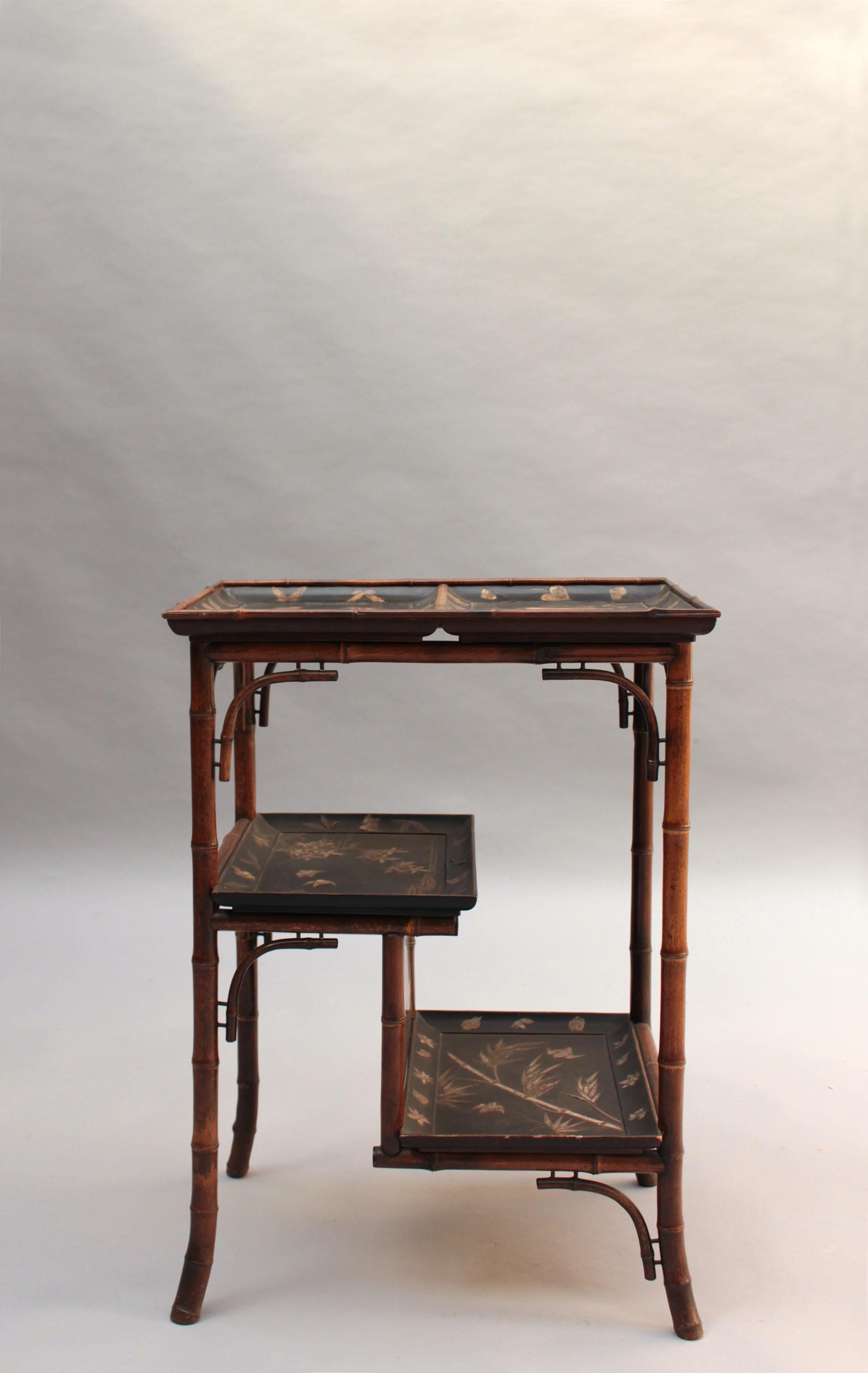 A fine French Napoleon III three-tiered side table with four ornamental bamboo legs and black lacquered trays/shelves with shagreen inlays of a still life with birds, butterflies, and florals.
