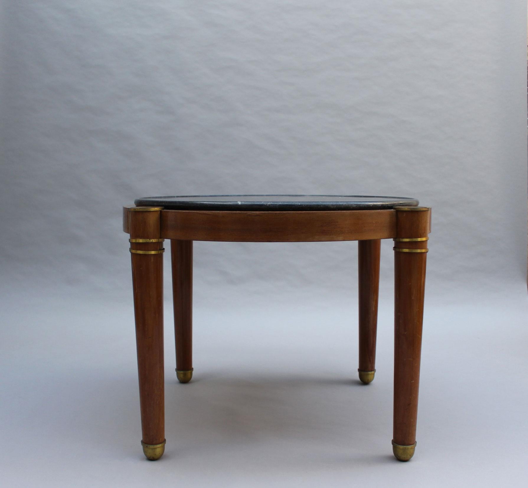 A fine French 1930s mahogany Guéridon with a dark grey marble (with small fossils) top and bronze details.