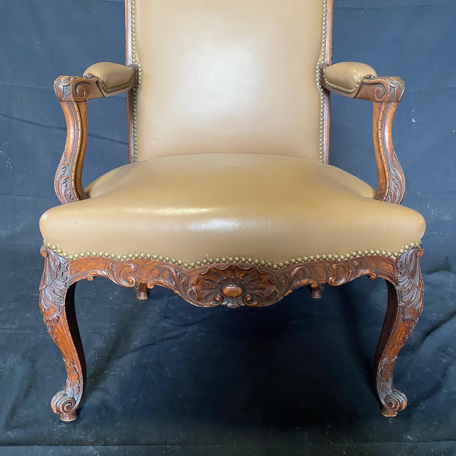 Bought in Avignon, France, this Louis XV leather chair has carvings on the edges of the entire back; unusual and lovely! Solid walnut, the chair features curved arms, upholstered with leather at the center with brass tack lining, flowing out from