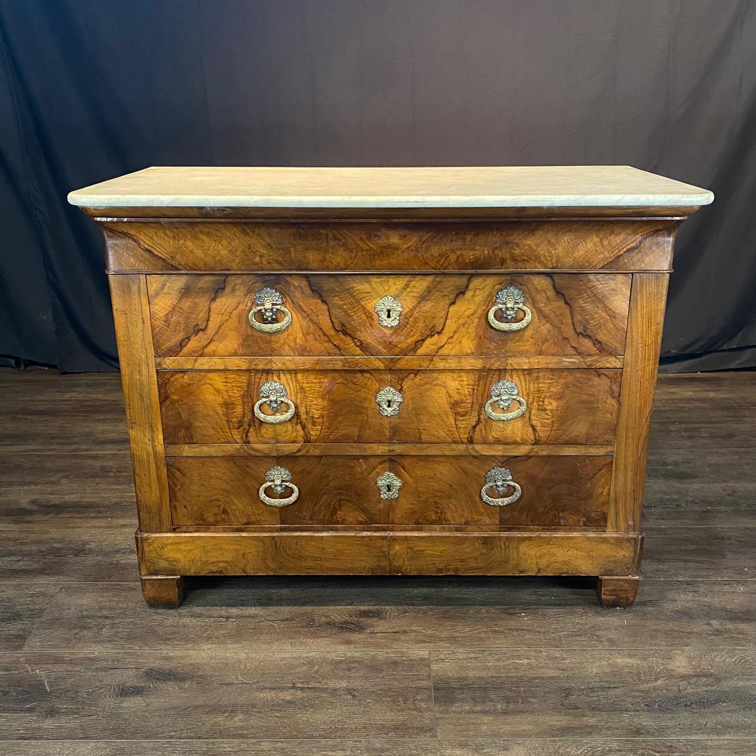 Elegant, refined yet understated medium size French Louis Philippe commode, or chest of drawers, from the 19th century, with exquisite bronze escutcheons and pulls, with wood of well-figured walnut and lovely original marble top. The drawers and
