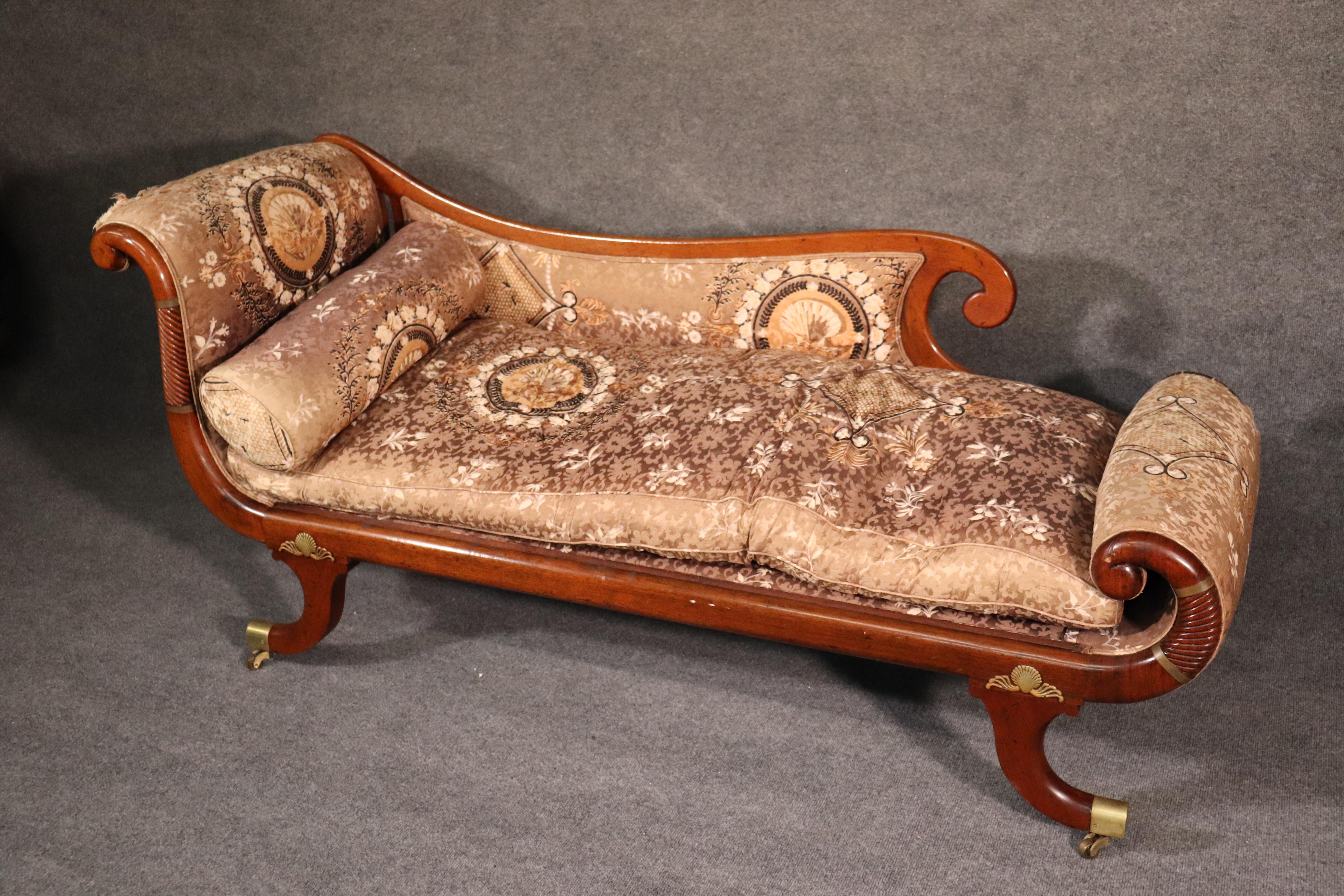 This is a spectacular and rare French recamier. The solid mahogany frame is adorned with fine solid brass inlay and feet with casters, also of brass. The upholstery is original and will need to be reupholstered. The cushion is filled with goose down