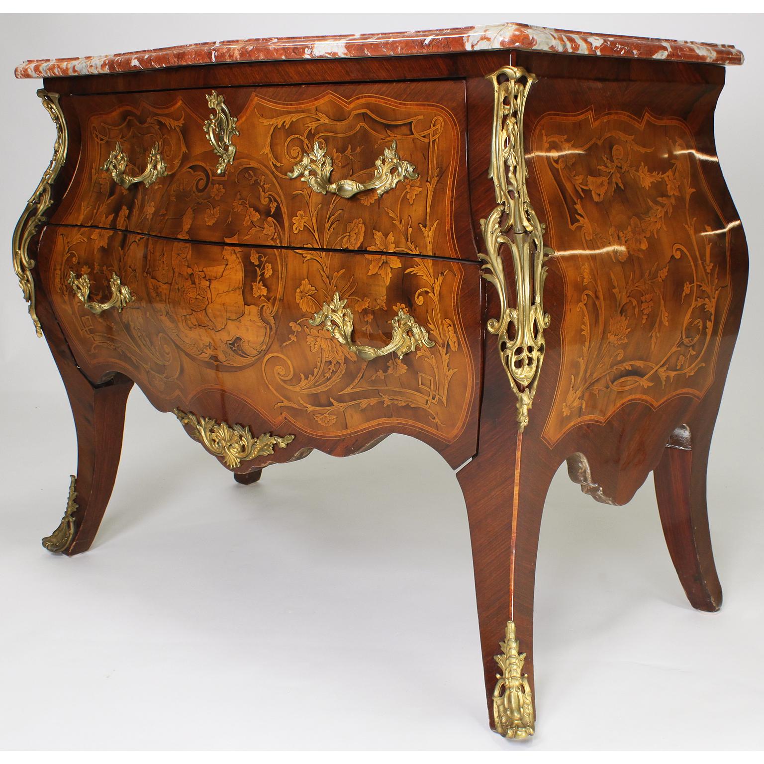 A fine French 19th-20th century Louis XV style gilt-bronze mounted tulipwood chinoiserie marquetry two-drawer bombé commode with a veined rouge royal marble top. The serpentine shaped body centered with a marquetry medallion depicting a seated
