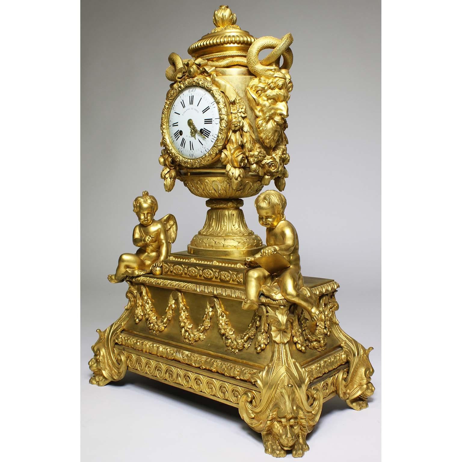 A very fine and Palatial French Louis XVI style figural gilt bronze mantel clock. The vase shaped case surmounted with a pomegranate-cast finial and flanked by large satyr mask handles fitted with intertwined gilt-bronze snakes, amongst floral