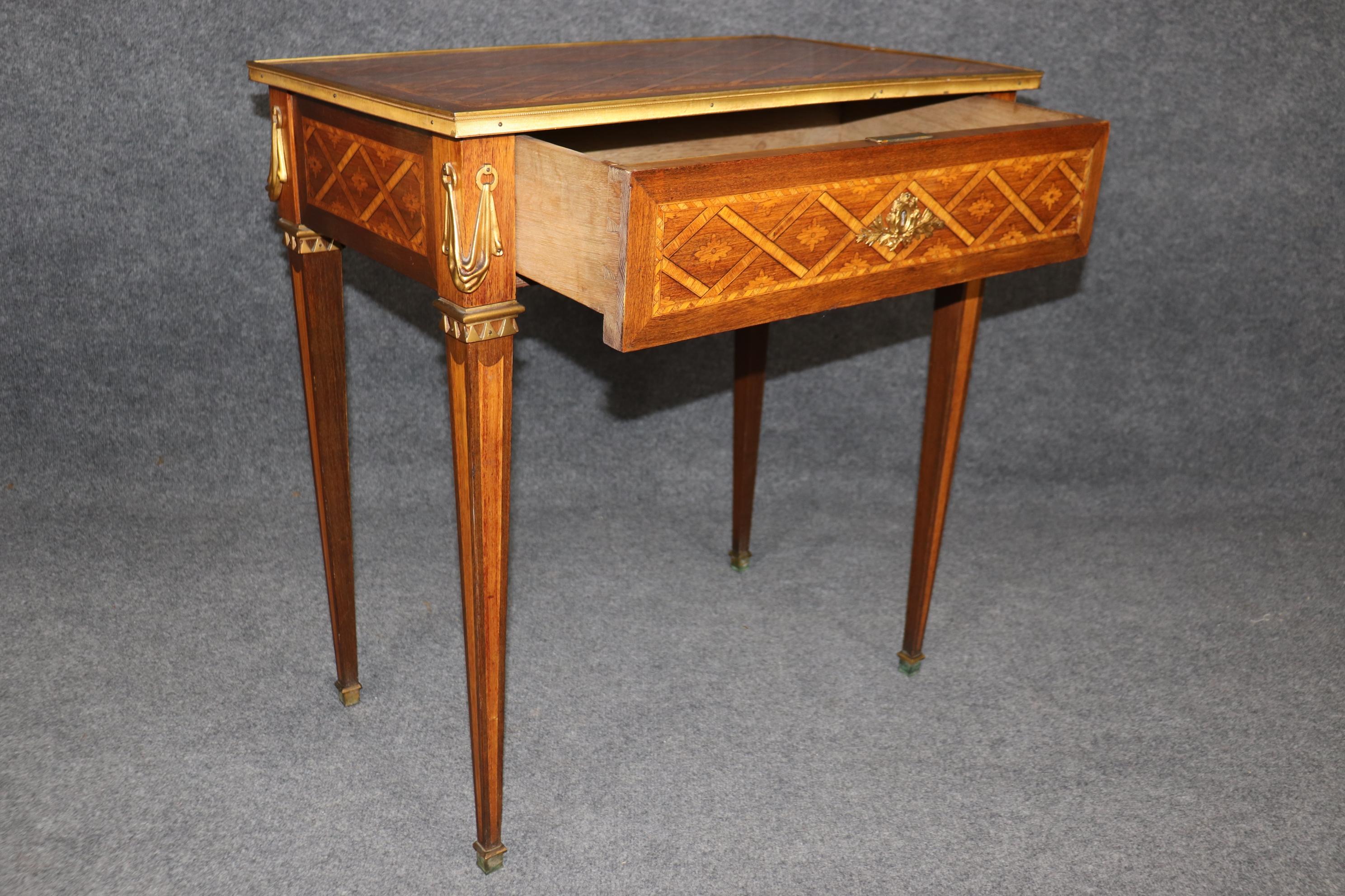 Il s'agit d'une superbe table d'appoint montée sur bronze, absolument décadente, avec un seul tiroir et une marqueterie de bois de tulipier et de bois de roi d'une beauté à couper le souffle. Le bronze doré est superbement moulé, et la finition est