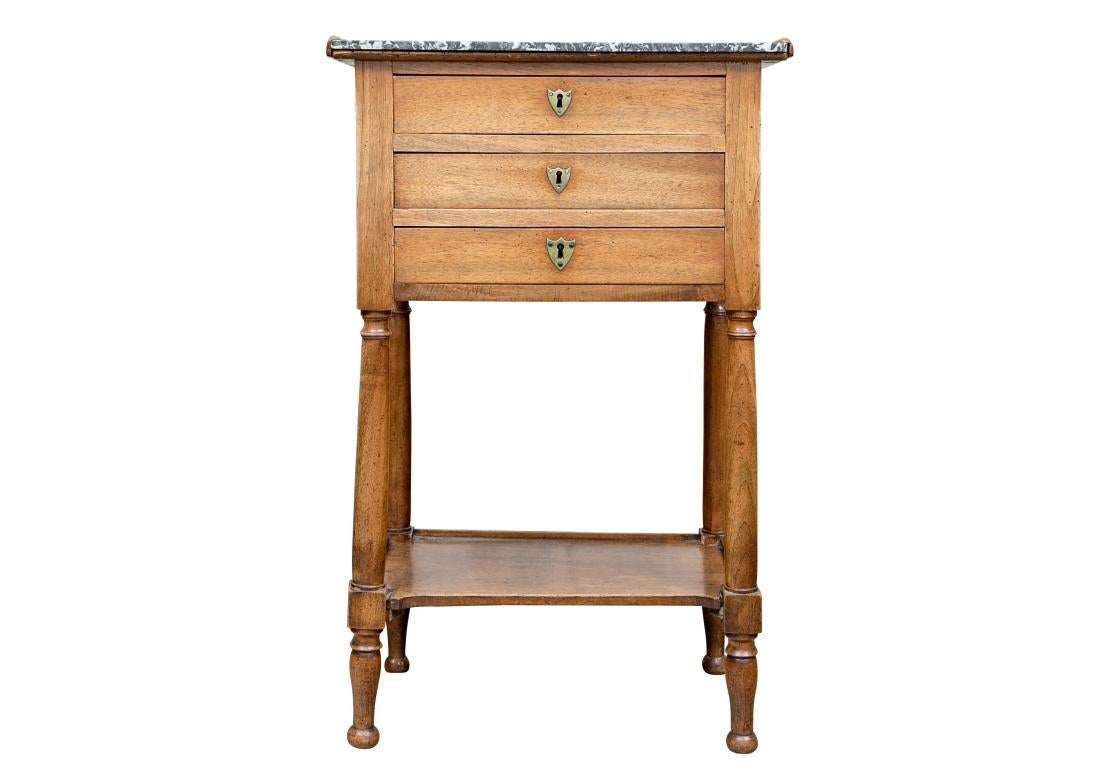 Un meuble à tiroirs en acajou de style Louis XVI, datant de C.I.C. (1810), avec un plateau en marbre gris veiné de blanc. Le bois est usé jusqu'à obtenir un ton châtaigne et le toucher est très doux et usé par le temps. De forme française