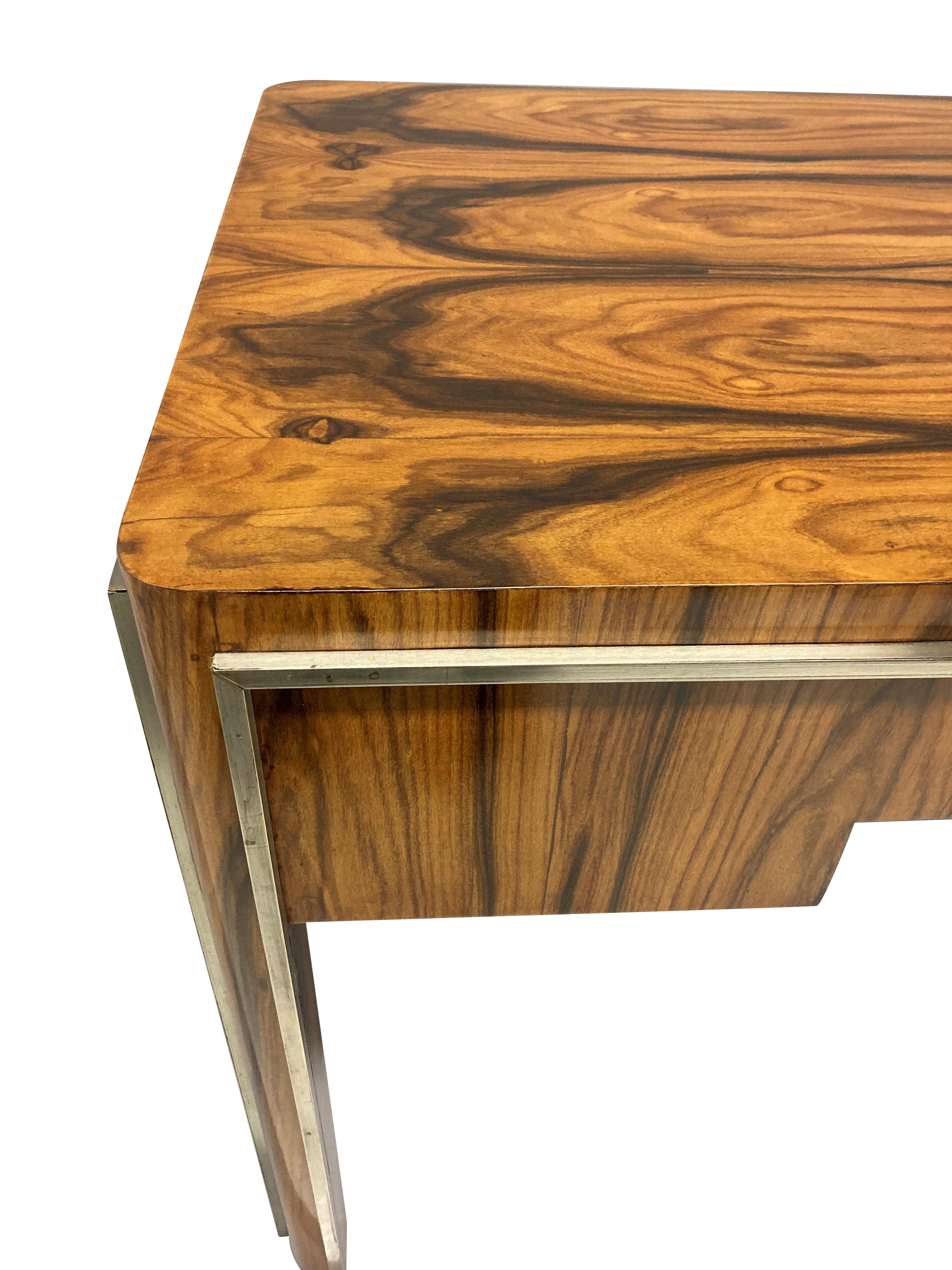 Una bella scrivania francese in legno di macassar, con tre cassetti centrali e con bordi e maniglie cromati.