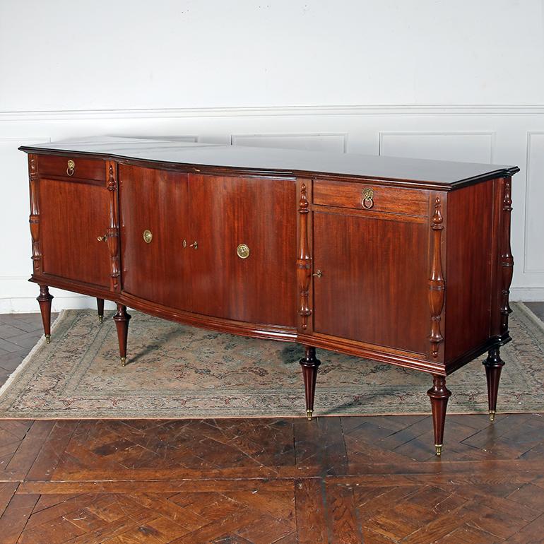 A French, mahogany bowfront buffet, the frieze with two drawers and four  doors below enclosing adjustable shelves, on turned legs with original brass sabots.