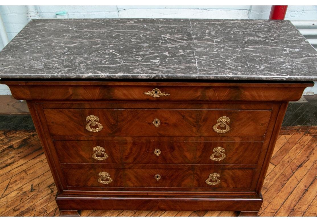 A very fine and beautifully made book matched flame mahogany chest with conforming gray marble overhanging top. With a cavetto from top narrow drawer with compartments over three long dove-tail constructed drawers. All drawers with book matched