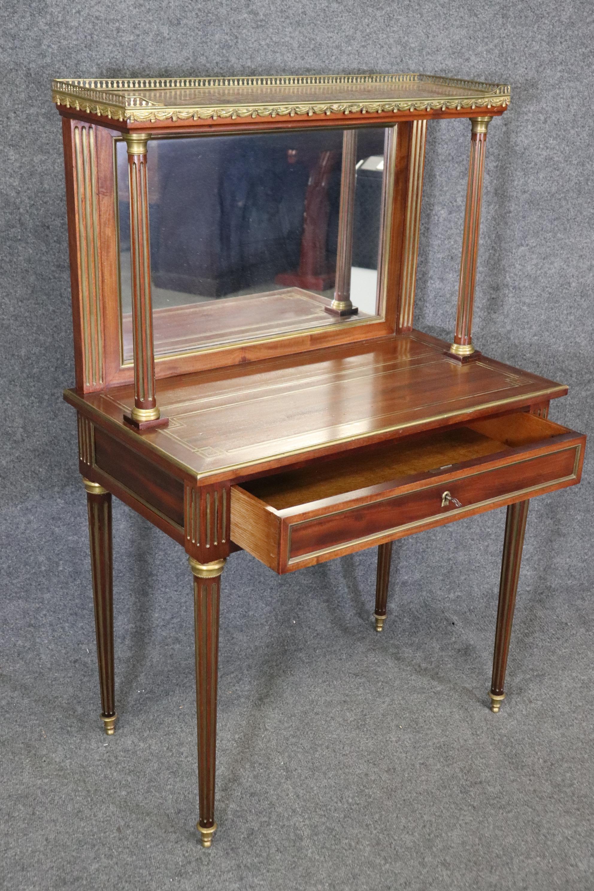 This is a superbly crafted antique French Directoire style brass inlaid and bronze mounted secretaire desk or ladies vanity. The piece is perfect for paying bills or using as a makeup vanity. The desk features a beautiful slab of marble on top and