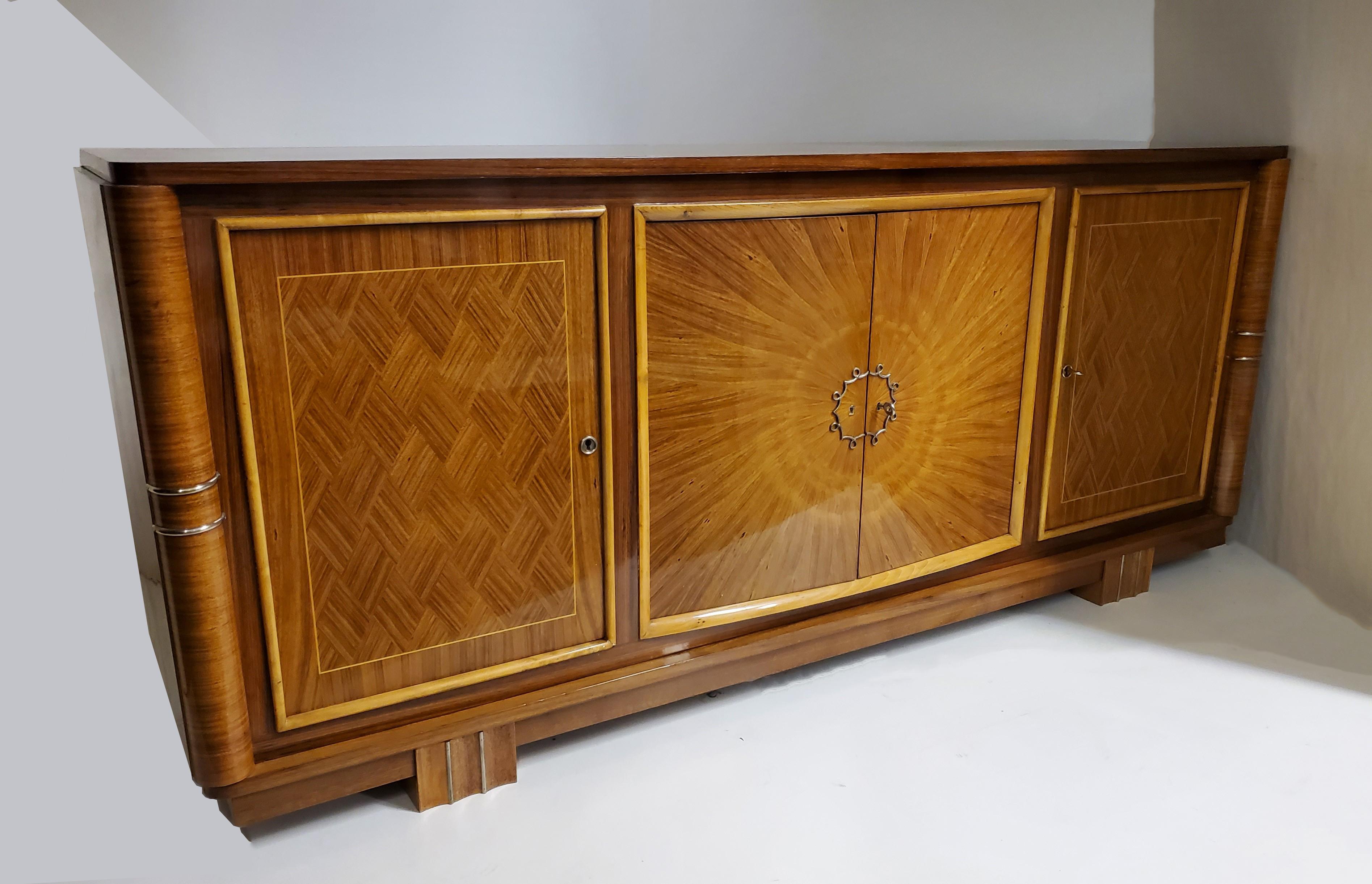 A beautifully crafted original French Modern three door wood cabinet with sunburst center doors and parquetry side doors and top attributed to Lucien Rollin. The sunburst center doors feature an inlaid wood radiating pattern that mimics the rays of