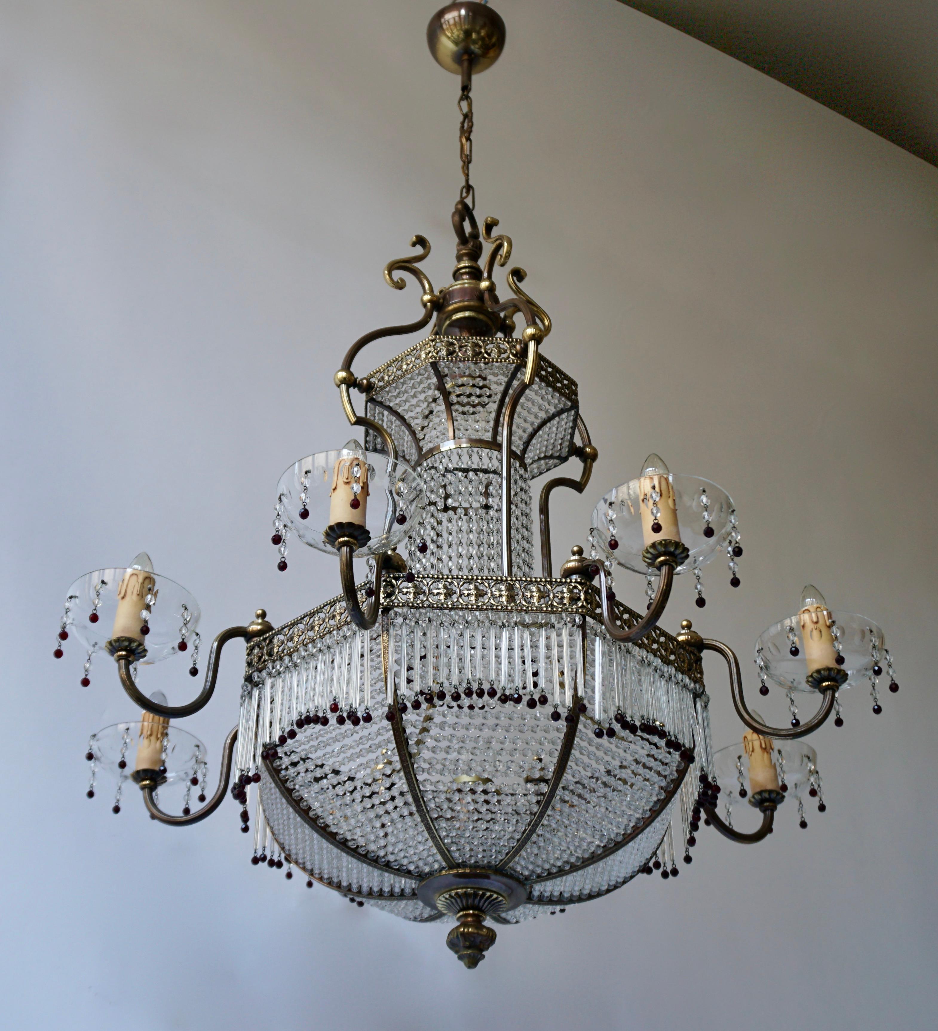 This beautiful French sac a perles chandelier has a copper wire mesh frame that is hung with hundreds of small glasses. The luster was made in Southern France circa 1950 and is in good condition. It has eight arms with candles on the outside and 2
