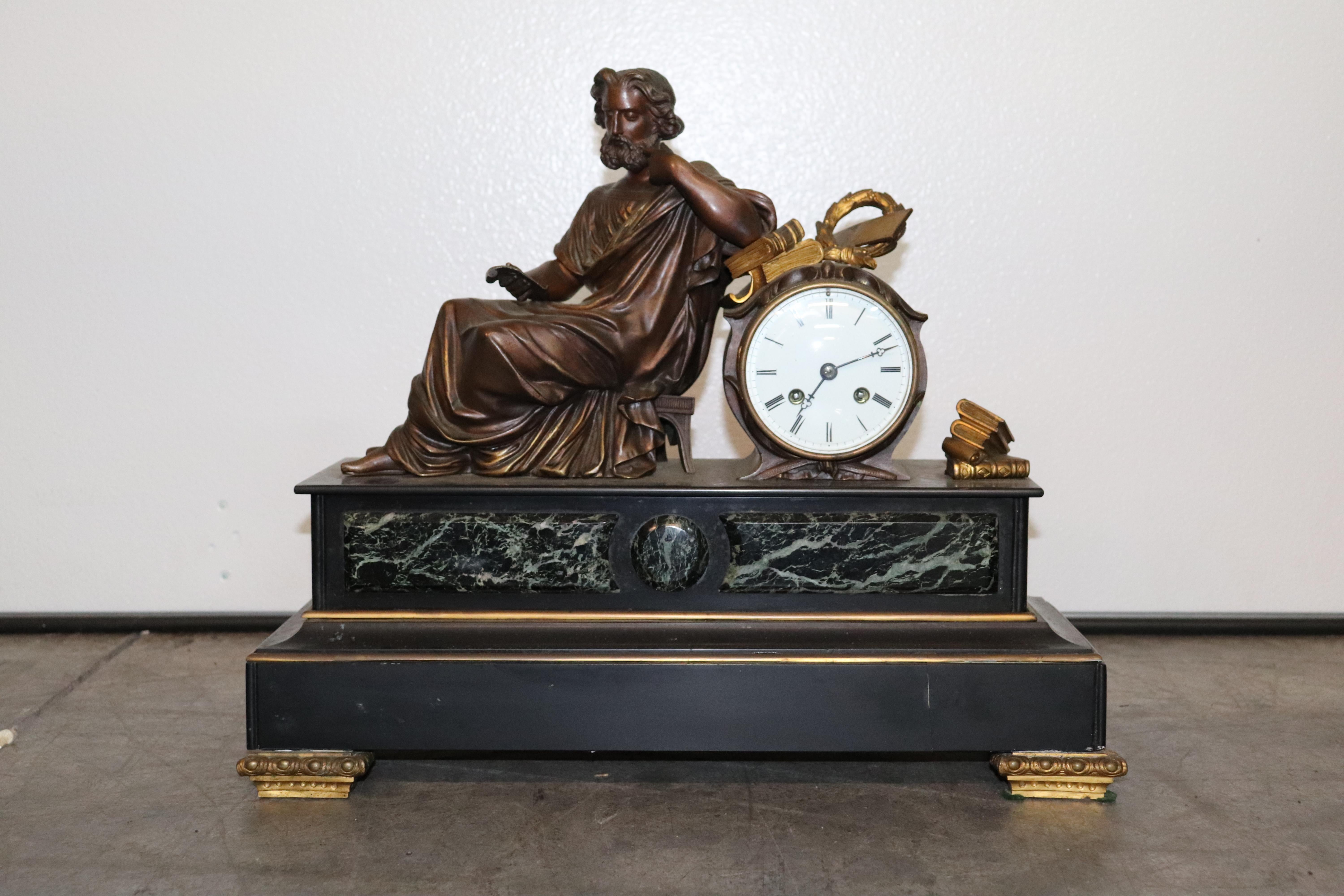 This is a gorgeous and very unique French mantle or mantel clock featuring a gorgeous figure of a scholar in robes recling while reading books. The clock is surmounted with verdi green marble and the base is solid slate or marble with bronze mounts.