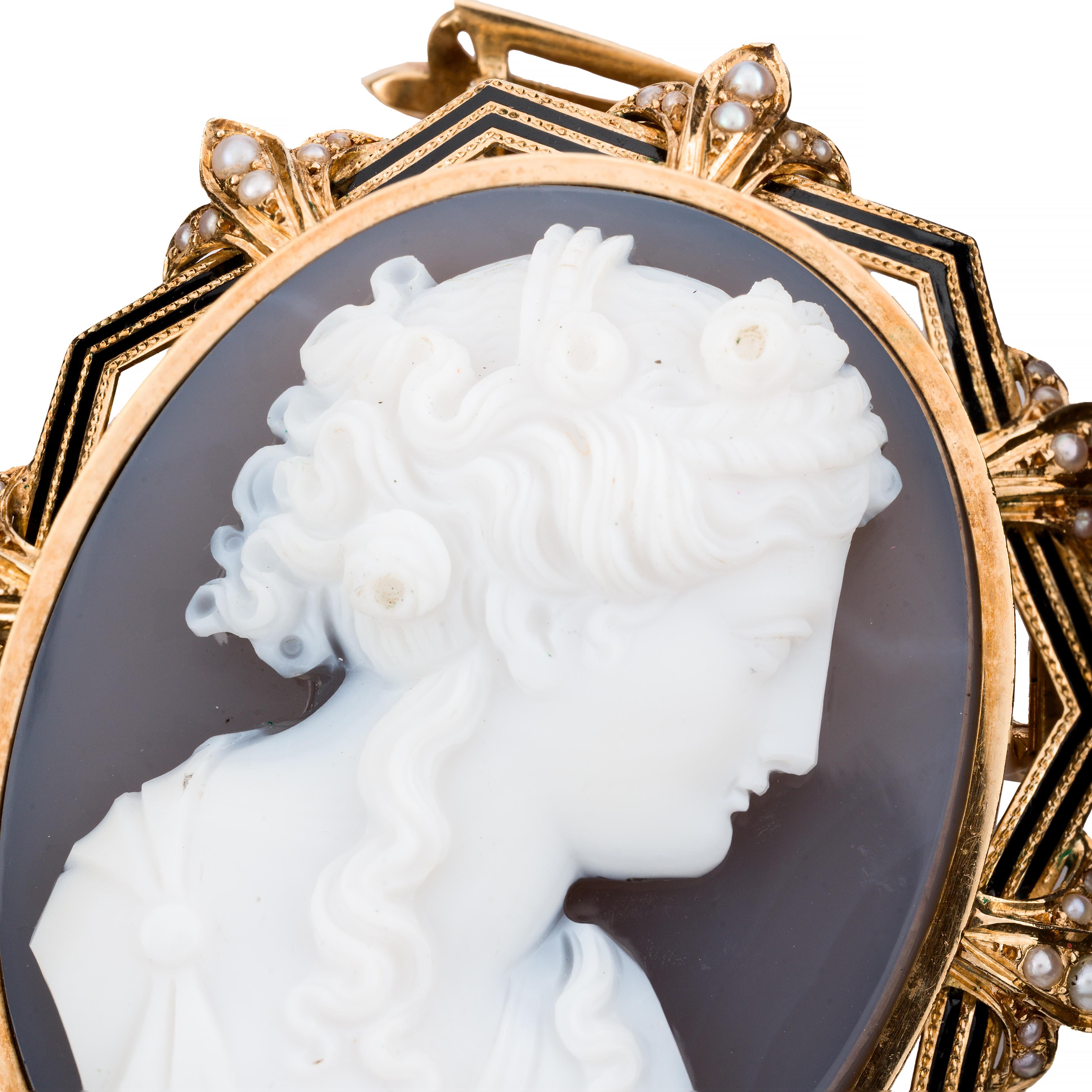 Aston Estate Jewelry presenta:

Un'elegante collana vittoriana con spilla e ciondolo del 1870, realizzata in Francia. 

Questo pezzo presenta un cammeo in pietra dura finemente dettagliato, incastonato in oro giallo 18 carati e ornato da perle