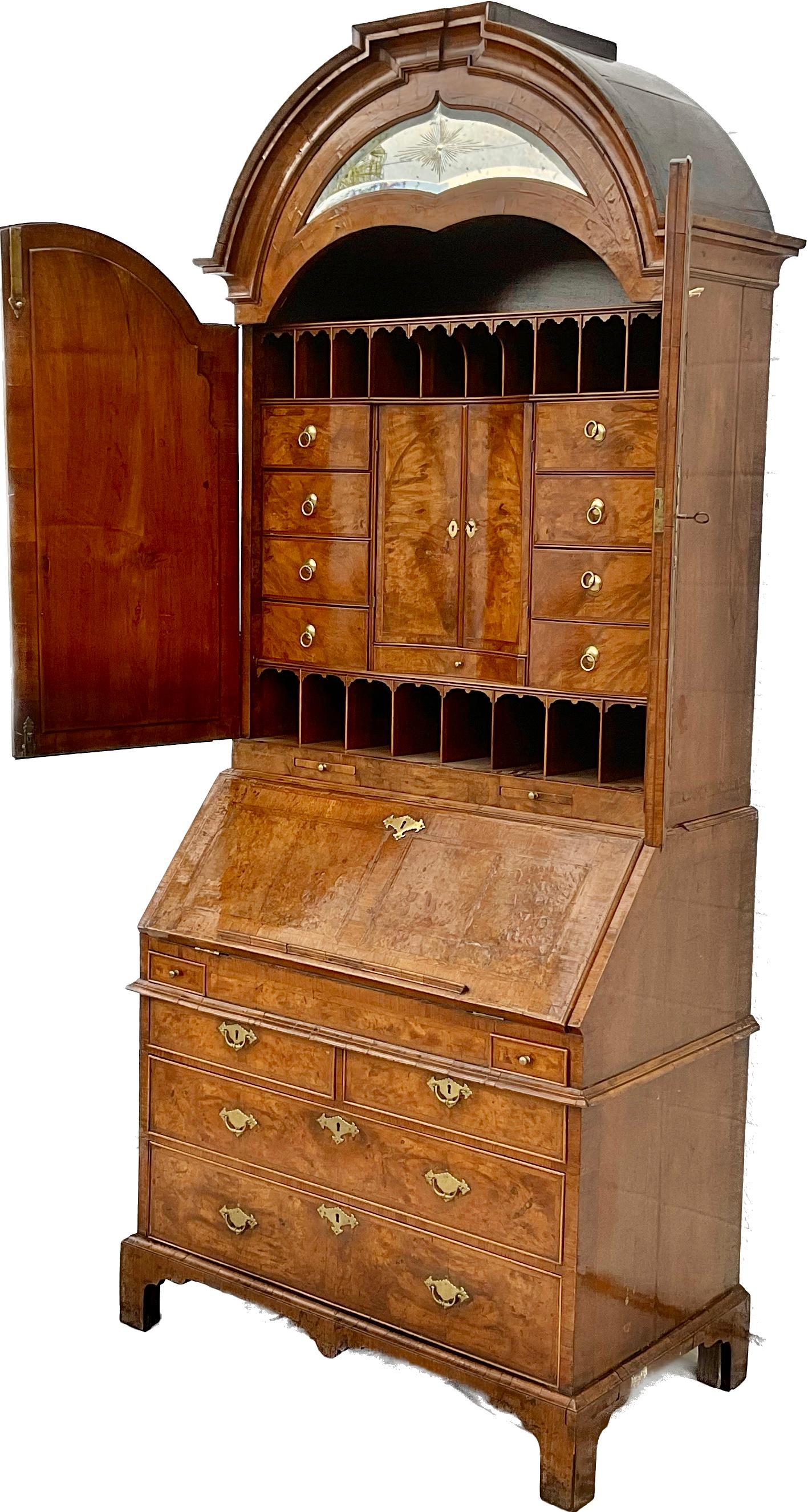 The best English Queen Anne / George I burl walnut secretary bureau bookcase in two sections. The upper arched top portion with a molded and domed cornice inset with mirrored glass and etched with a sunburst. The two doors with original mirrored