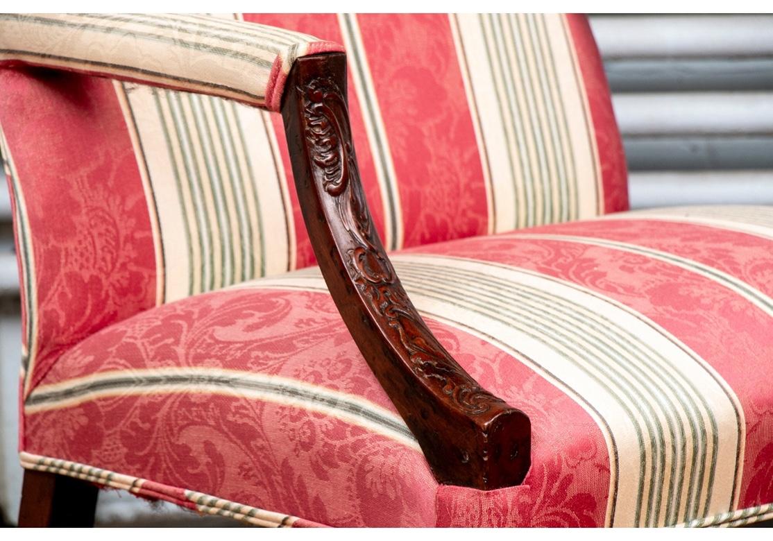 With an arched back and square seat. The down curved arms carved in foliate scrolls, the front legs with carved blind fretwork with interlaced and trefoil motifs, circa 1765. Splayed back legs with a stretcher, and an H-stretcher. Newly upholstered