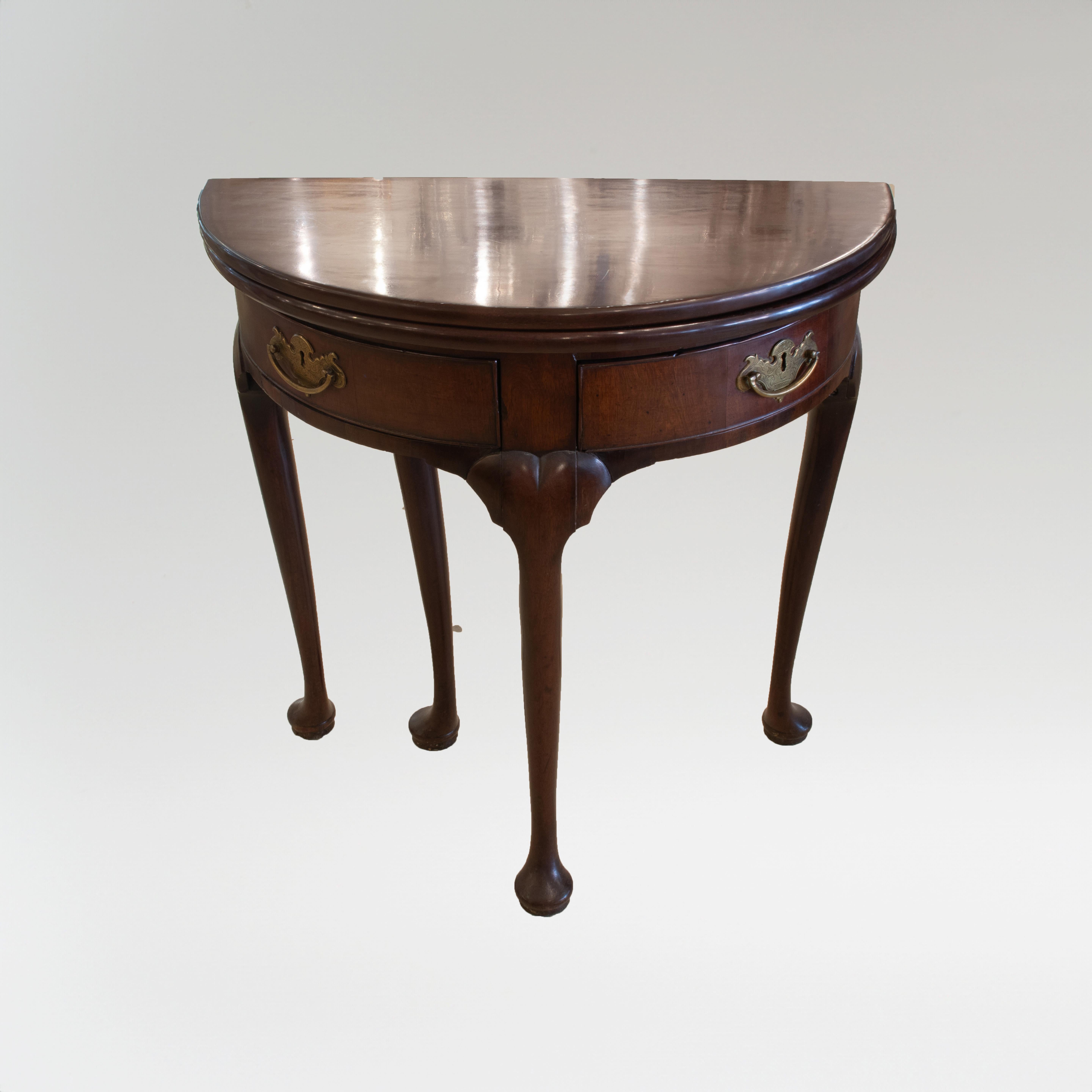 This is a fine George III English mahogany demilune table with two drawers that swing out. The George III style produced exceptional quality pieces that many collectors have deemed the finest examples of furniture design. During this time Georgian