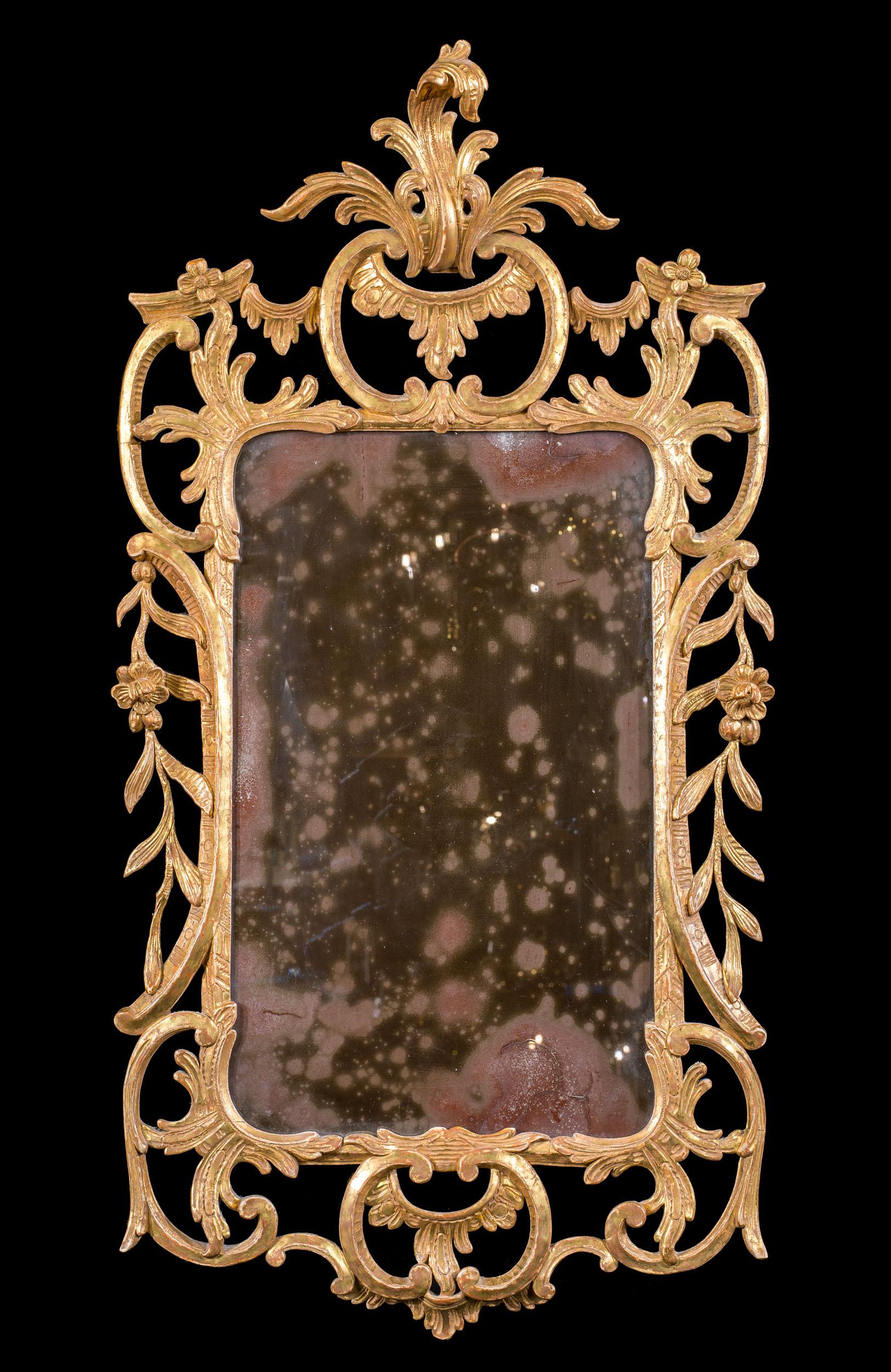 A fine gilt gesso George III wall mirror with delicate carving. The intricate frame has fine detailing throughout, including a well carved and delicate crest of foliate form and flowering vines and foliage within a framework of c scrolls.
English,