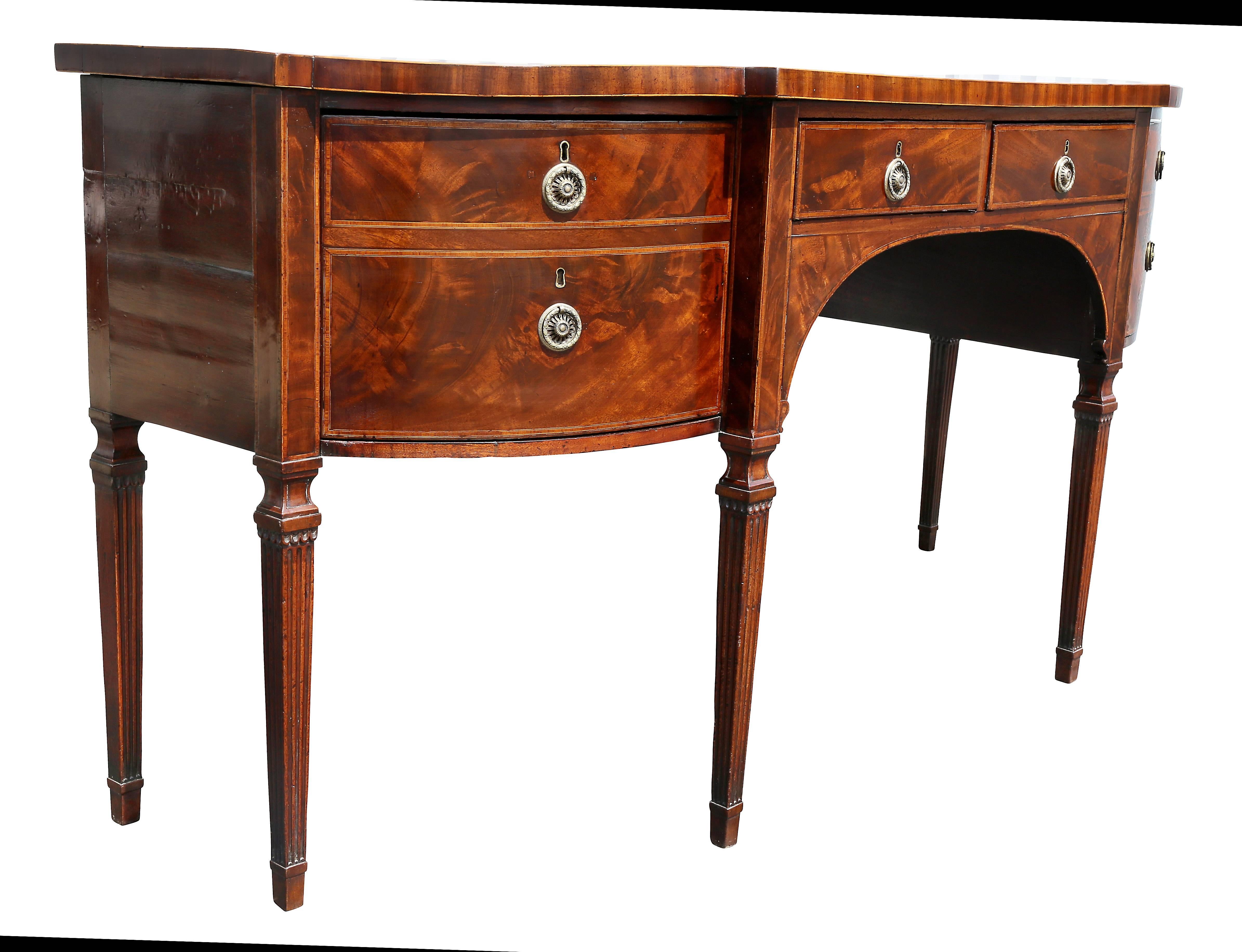 With bowed top and square back corners over a conforming case with banding and a central drawer flanked by two deep drawers raised on square tapered fluted legs headed by shaped carved squares.