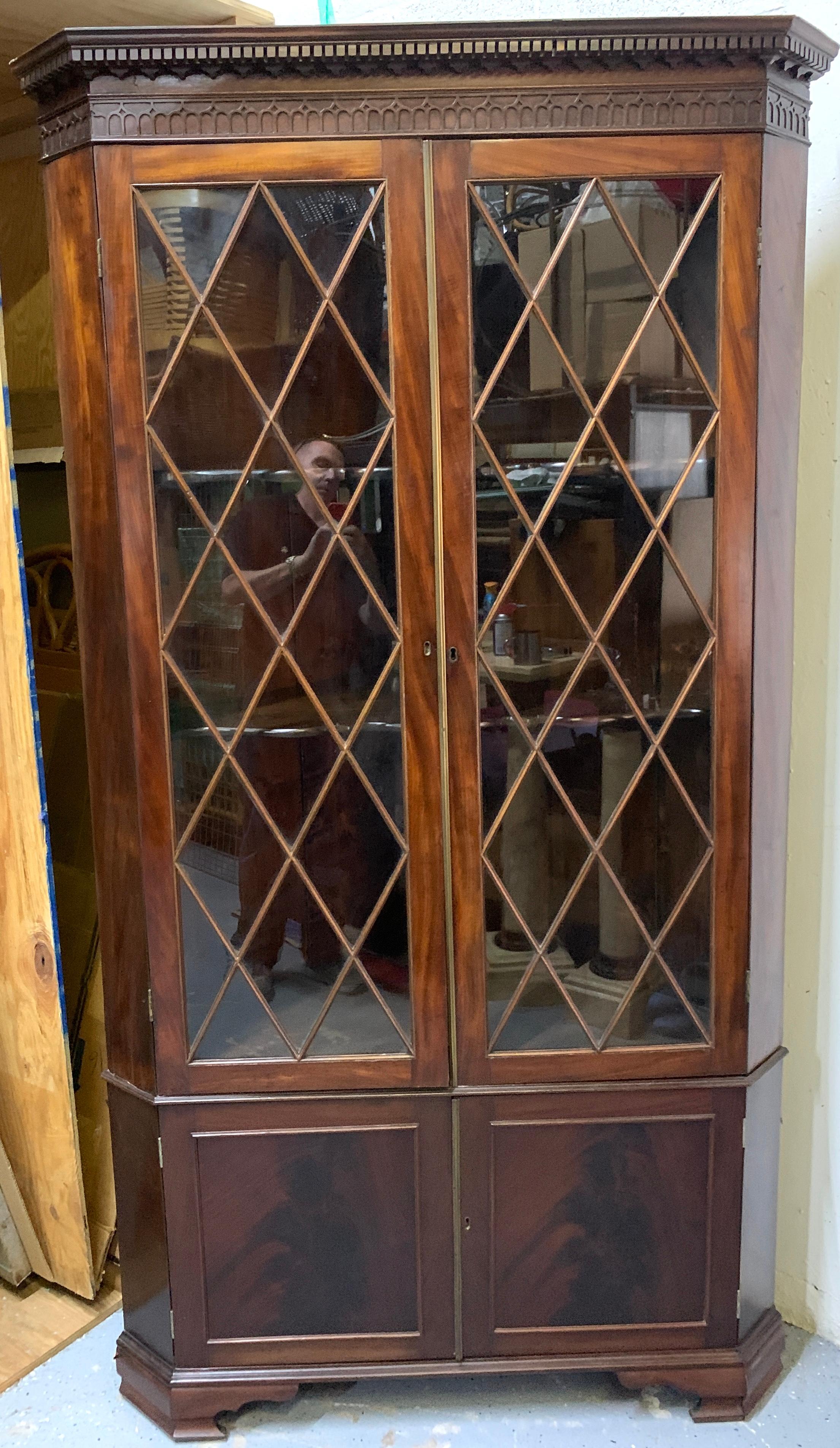 Fine George III mahogany corner cupboard, with fine dental molding with subtle Gothic frieze cornice. Fitted with two diamond patterned mullion glazed doors, the interior with two shelves. The lower part with two paneled doors, raised on bracket